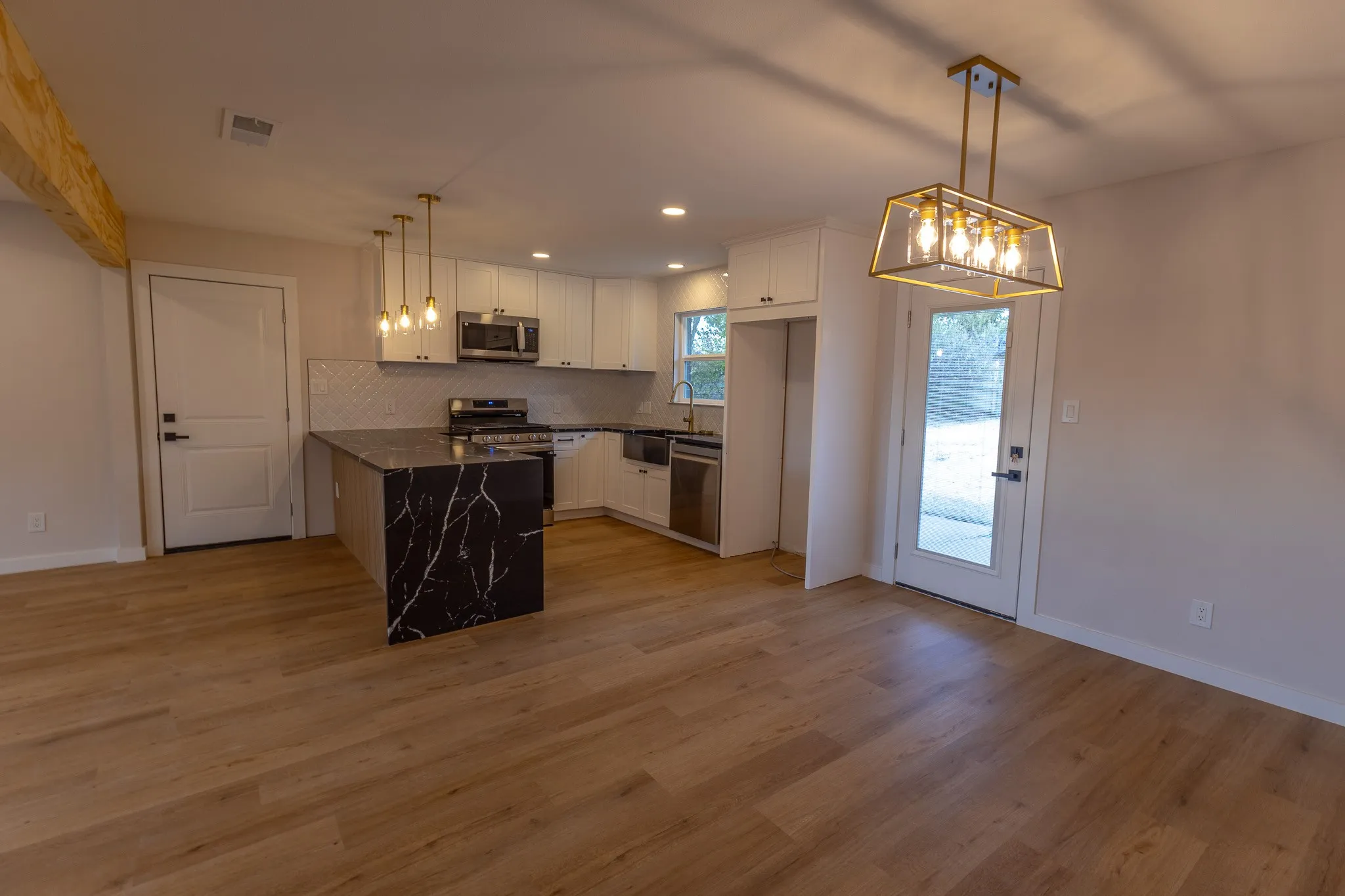 Kitchen featuring black marble-look countertops, white cabinetry, and stainless steel appliances