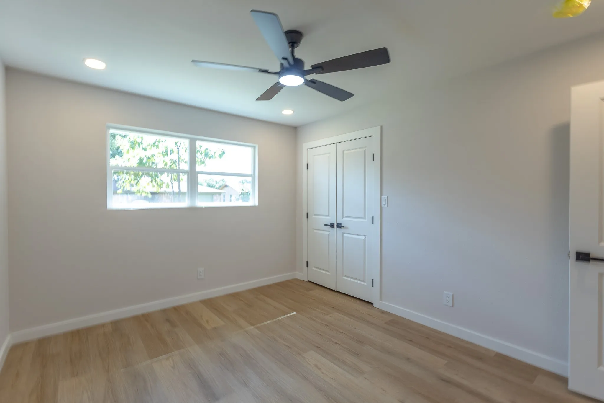 Bright and airy bedroom featuring wood-finish flooring, recessed ceiling lighting, and a ceiling fan with integrated light fixture