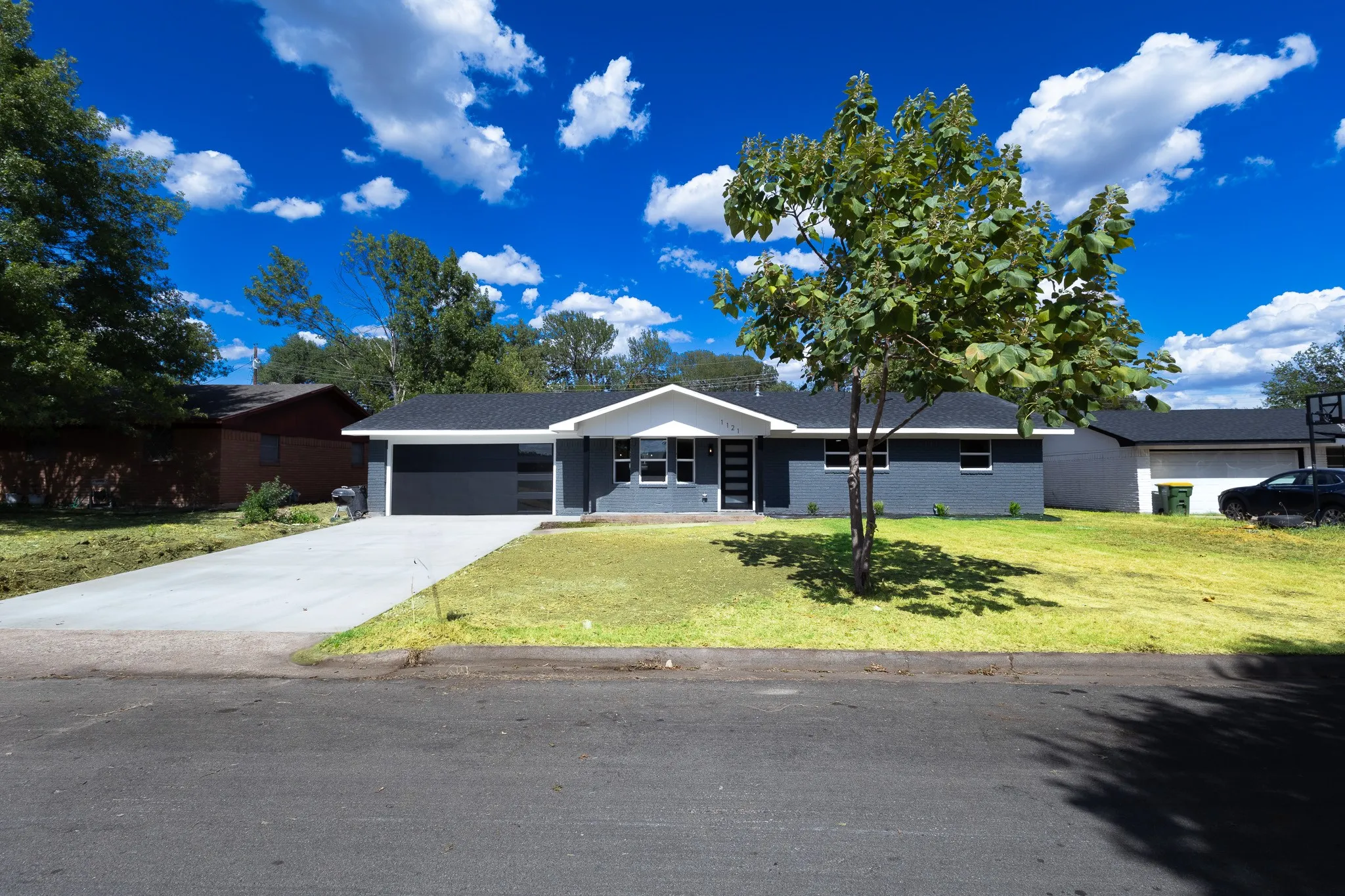 Contemporary exterior with a dark gray brick facade, white trim, and a black shingle roof
