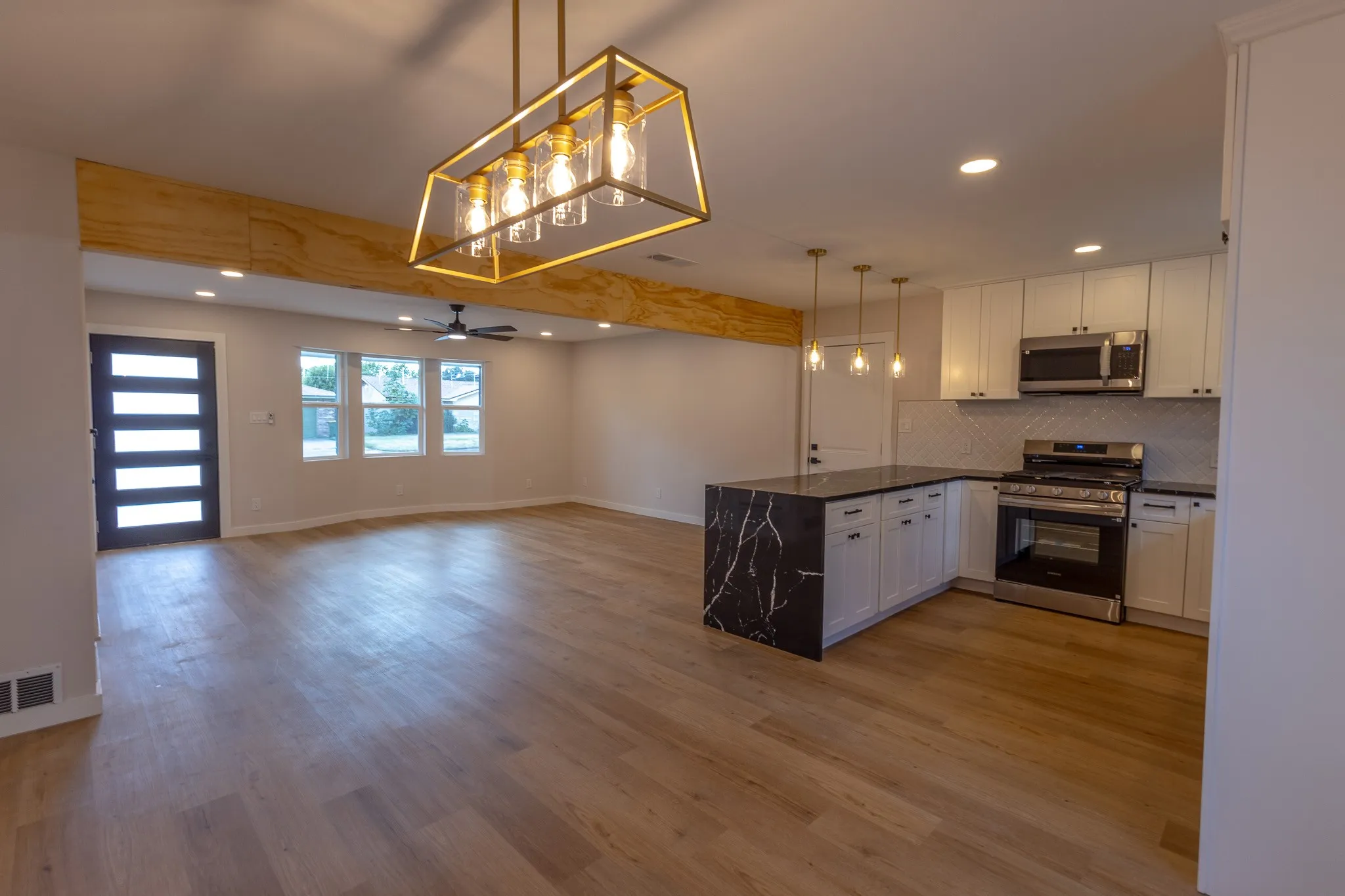 Open-concept living space featuring wood-finish flooring, a modern chandelier, and recessed lighting
