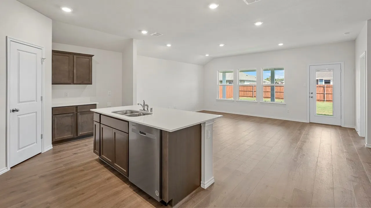 Open-concept living area with wood-finish flooring, recessed lighting, and a kitchen island featuring a stainless steel dishwasher