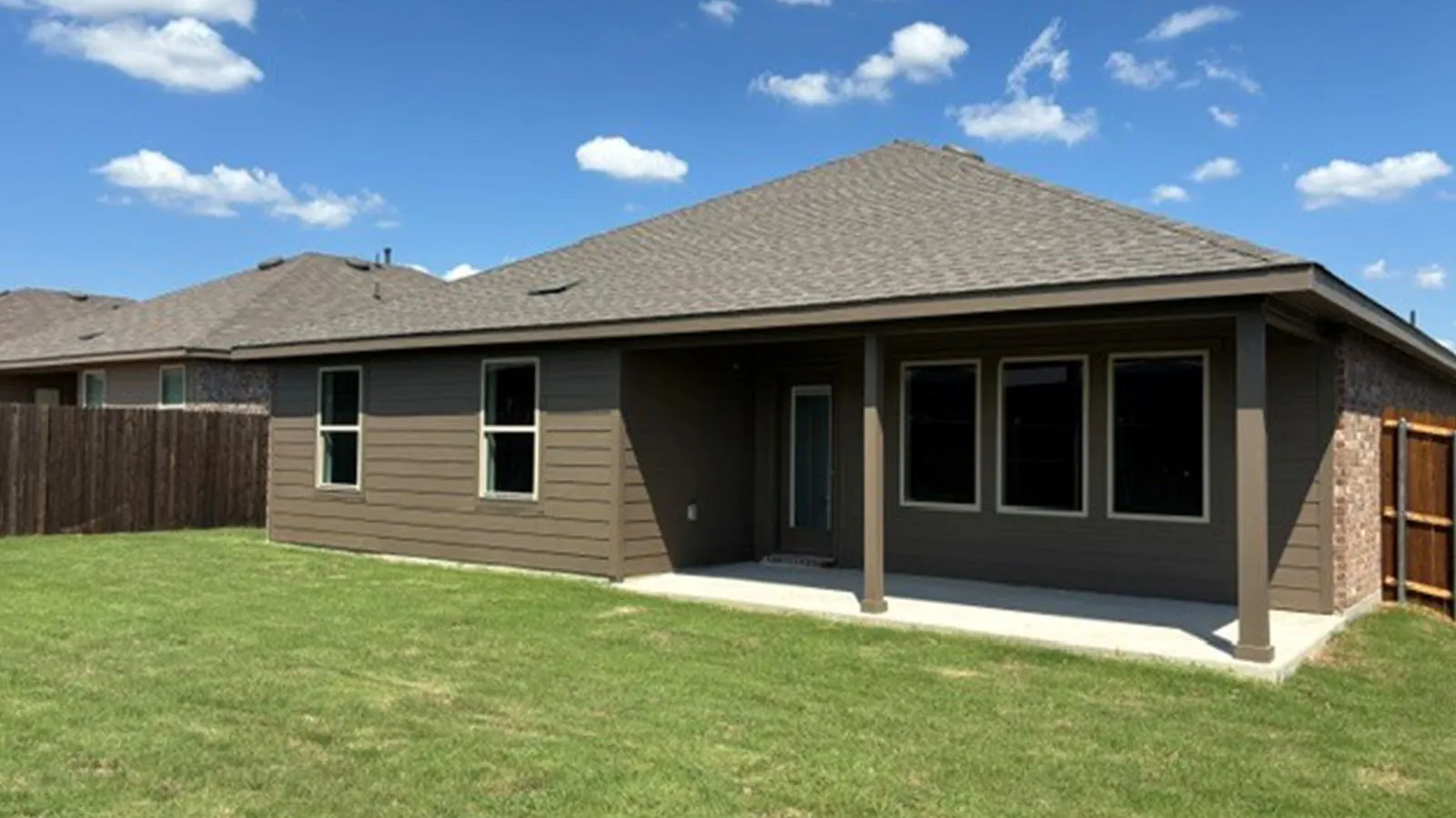 Expansive backyard featuring a manicured lawn, a covered concrete patio, and a privacy fence