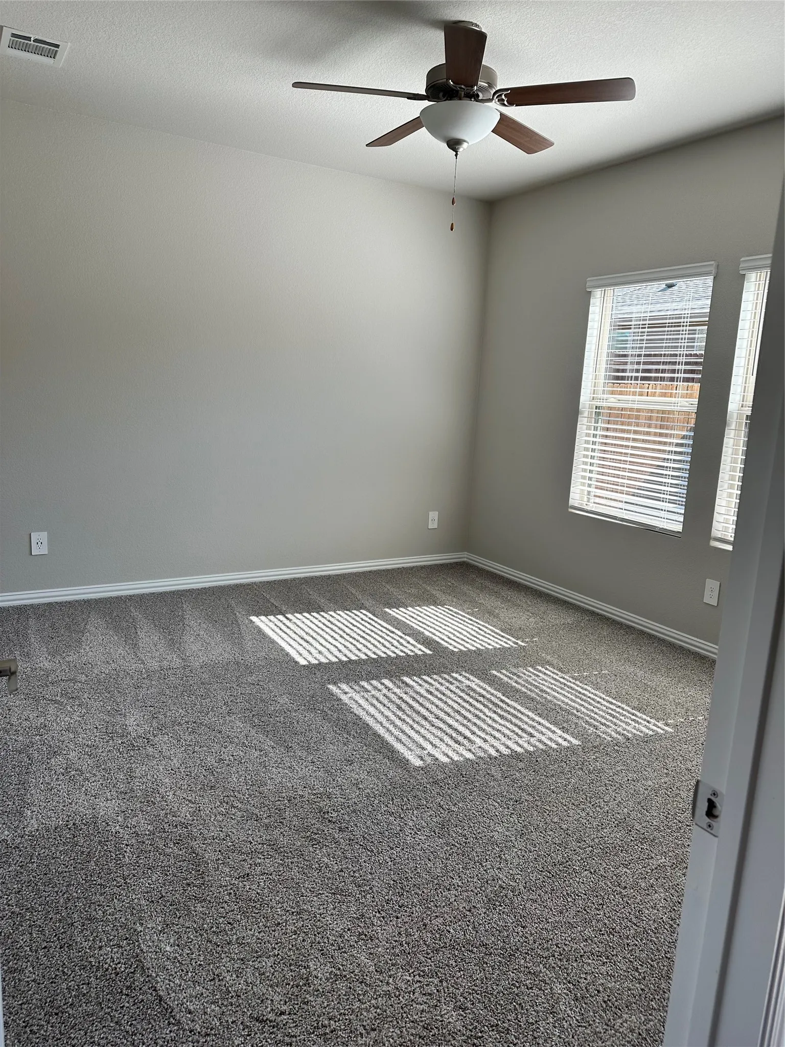 Carpeted flooring, neutral wall tones, ceiling fan with light fixture, and window blinds