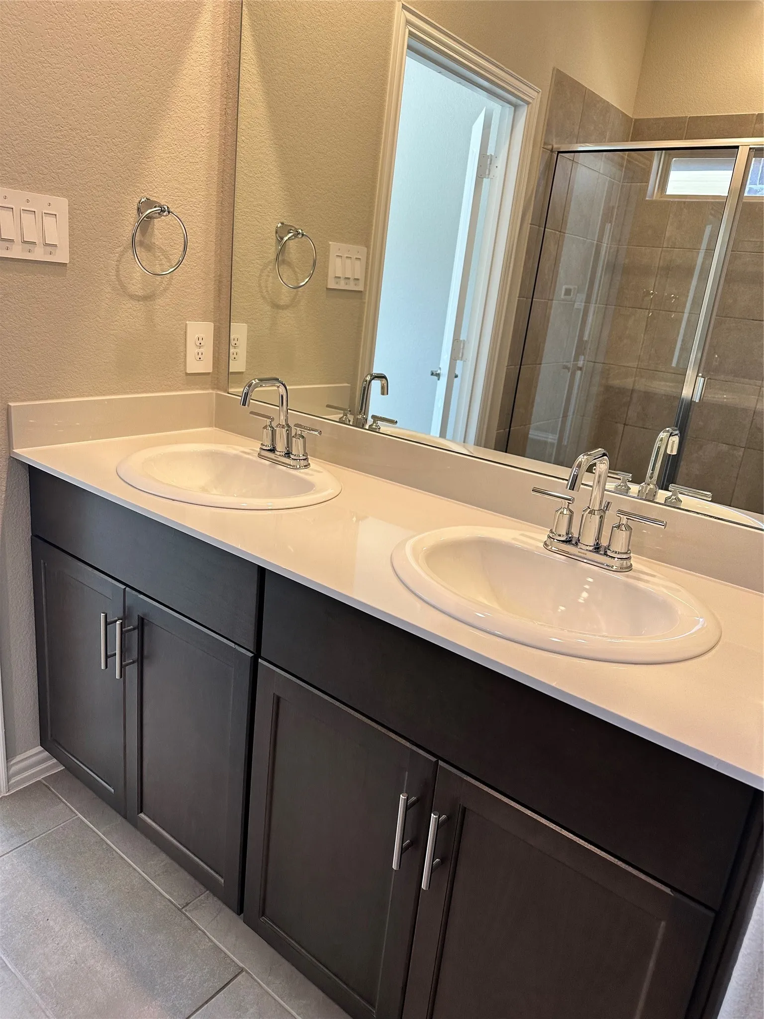 Double vanity with white oval sinks, chrome faucets, and dark wood-finish cabinetry