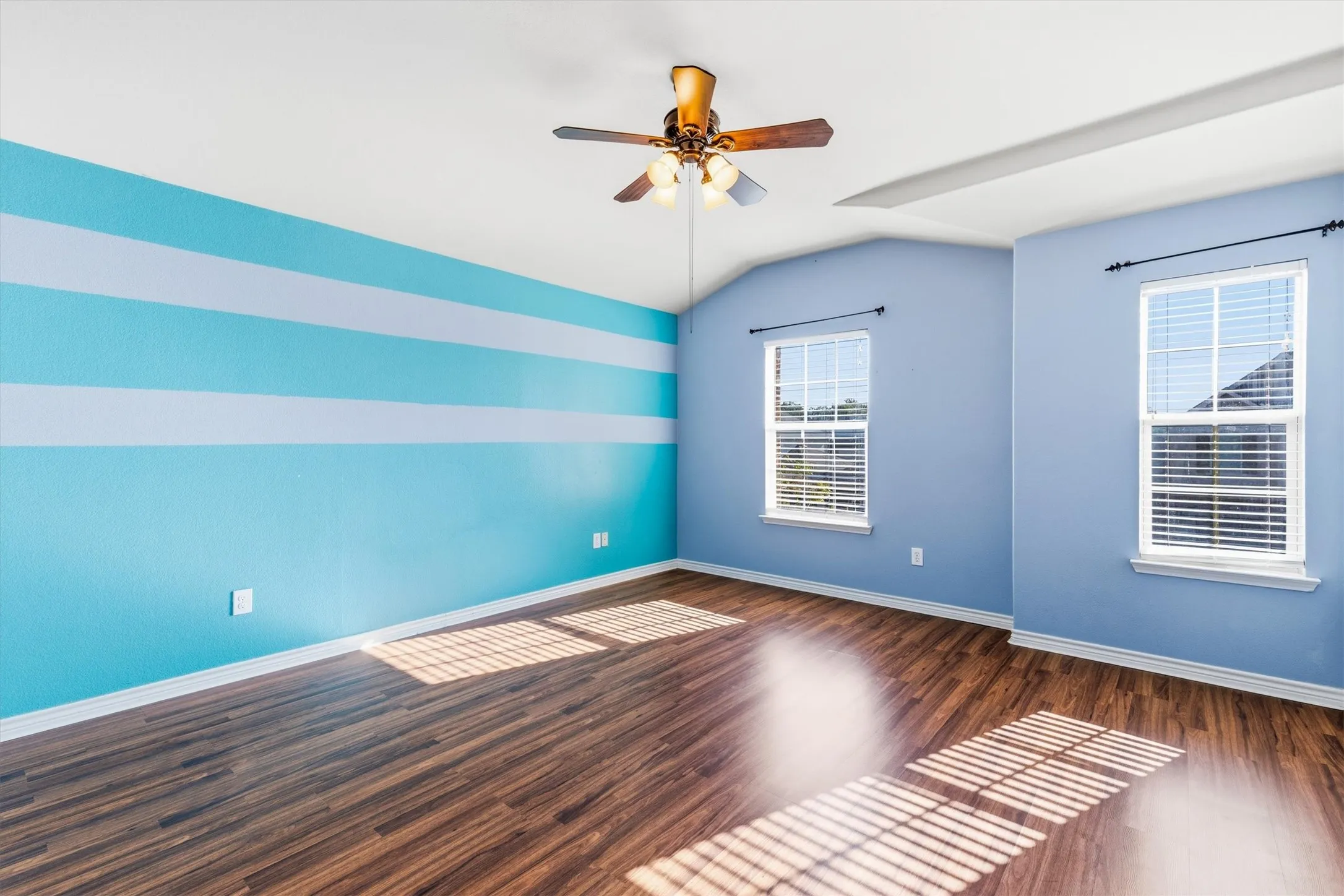Second floor bedroom with windows for natural lighting as well as a ceiling fan and closet.