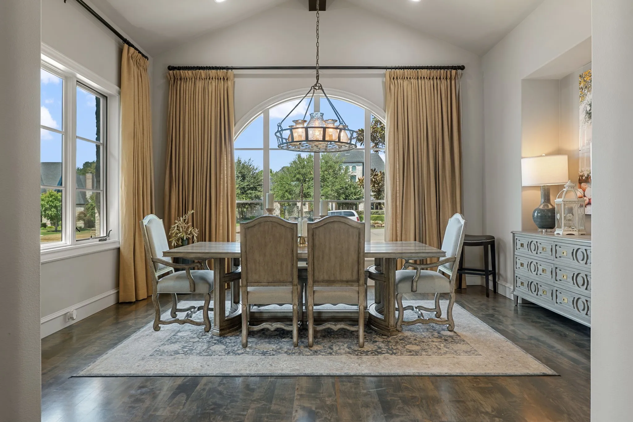 Vaulted ceiling with an ornate chandelier, arched window, wood-finish flooring, and recessed lighting