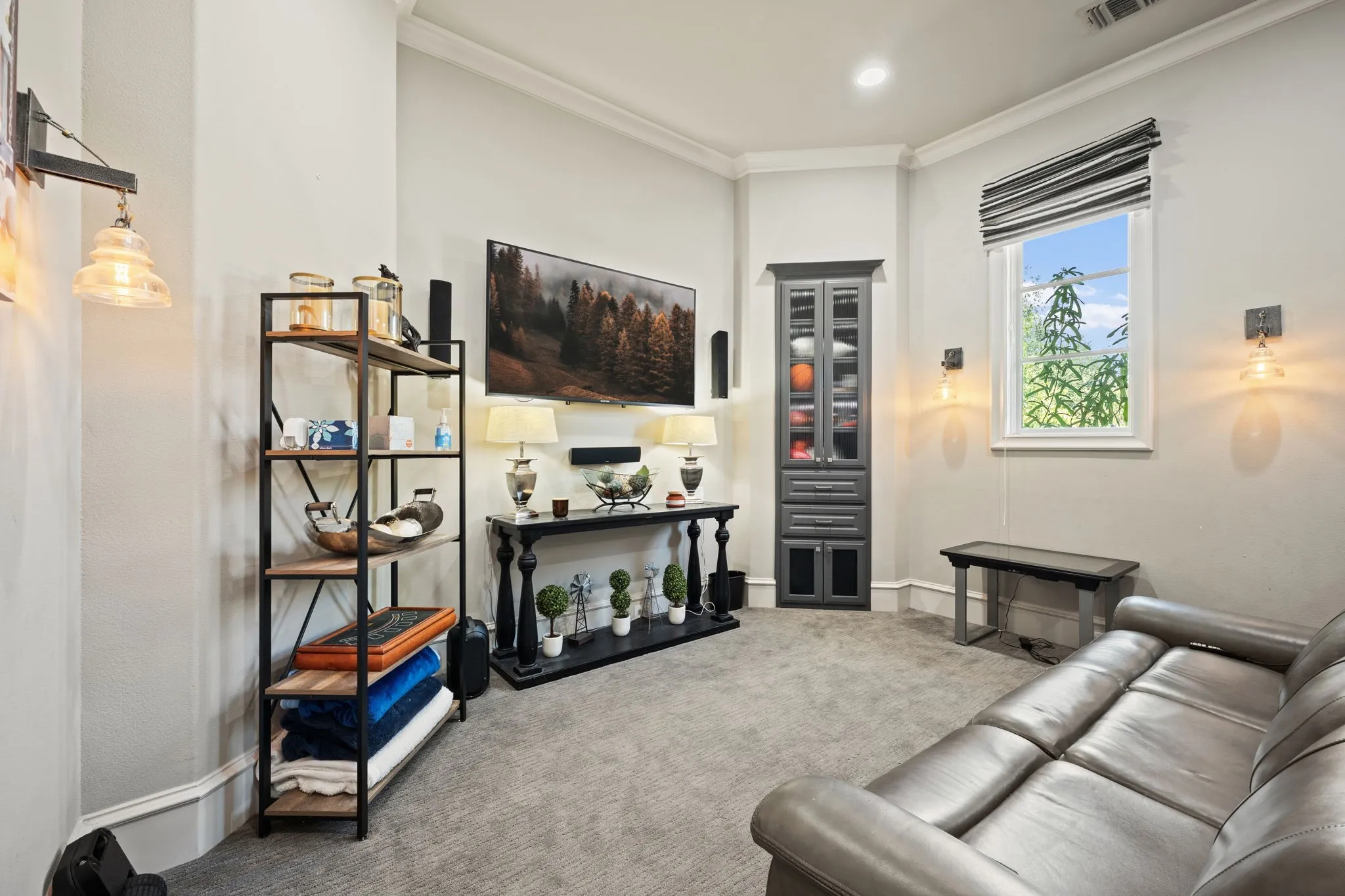 Wall-mounted sconces, recessed lighting, built-in cabinetry with glass inserts, transom window, and crown molding