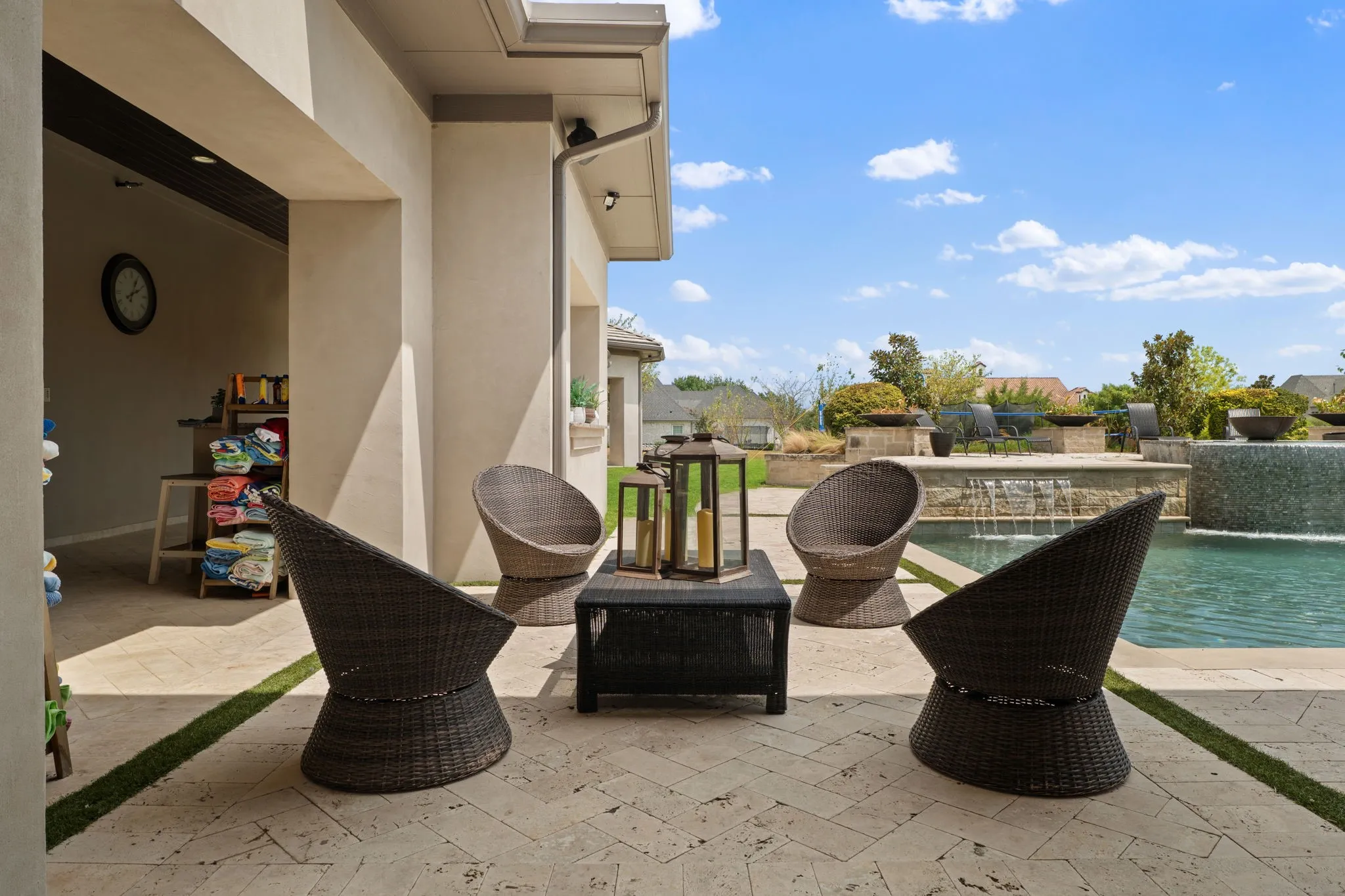 Travertine patio featuring an integrated swimming pool with a waterfall feature
