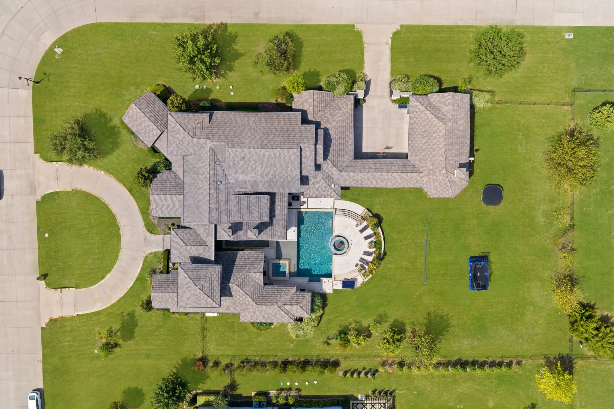 Expansive property featuring a circular driveway, multi-gabled roofline, substantial backyard, private swimming pool, and a dedicated spa
