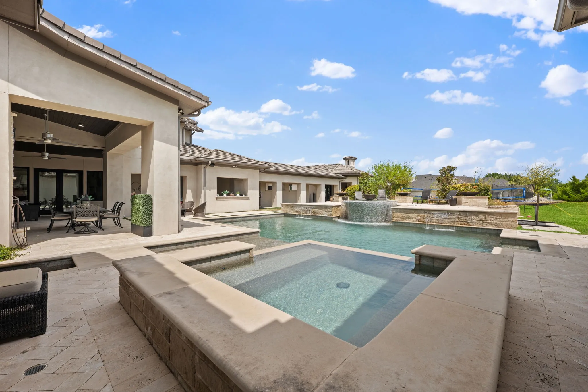 Expansive outdoor area featuring a custom pool, integrated spa, covered patio with vaulted ceiling, and a water feature