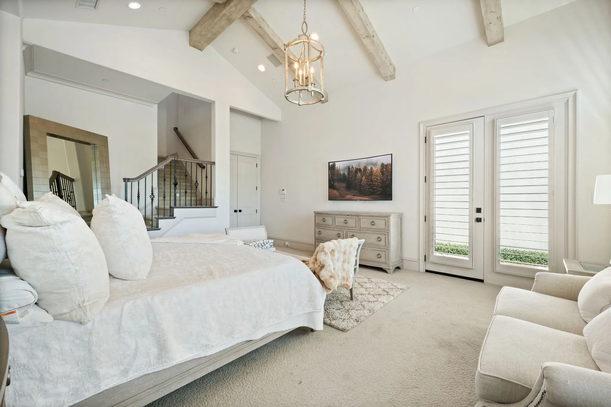 Vaulted ceiling with exposed wood beams, dual French doors with interior shutters, recessed lighting, and a staircase with wrought iron balusters