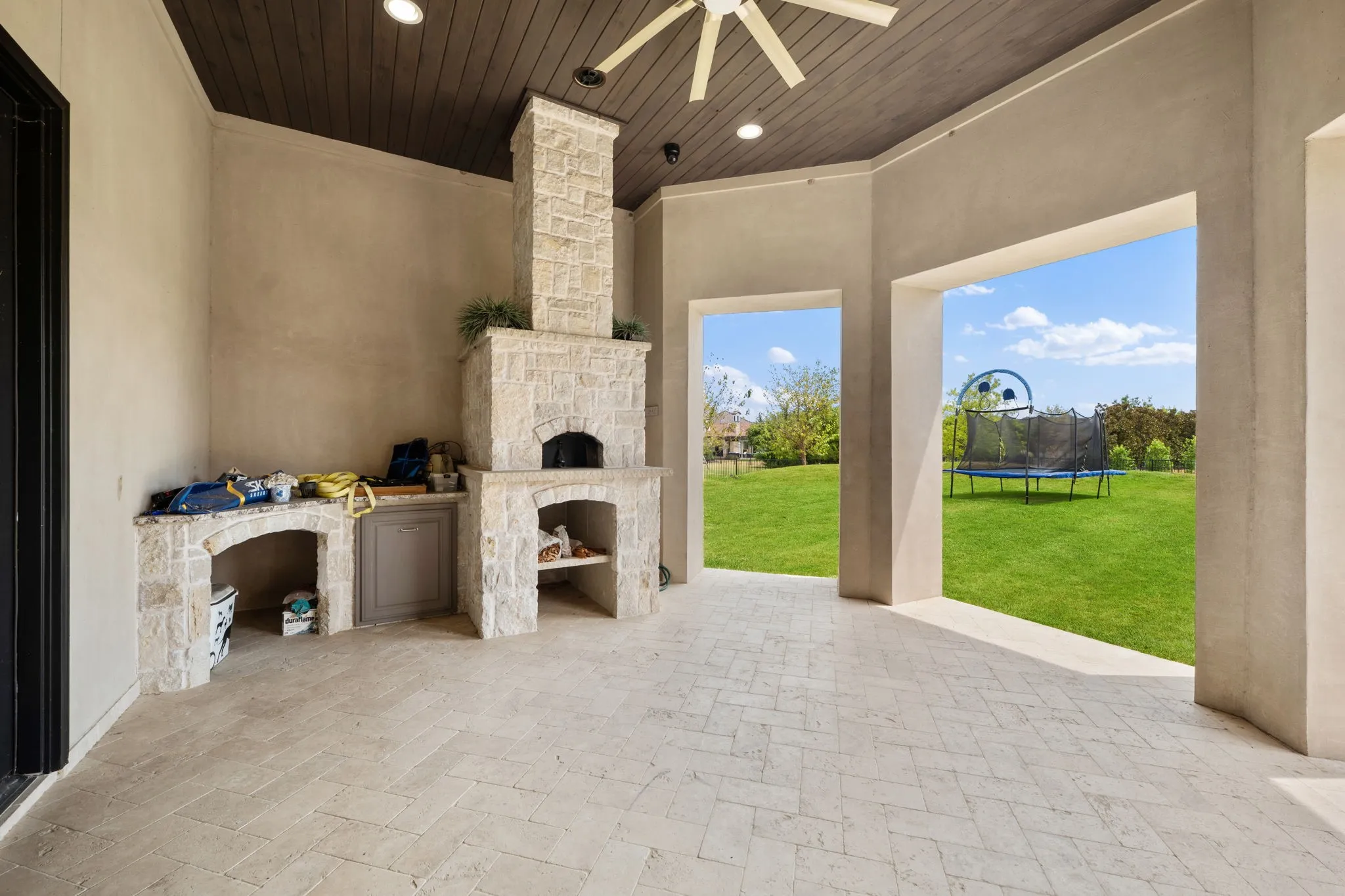 Covered outdoor patio featuring a stone-clad pizza oven, built-in counter space, and herringbone-patterned flooring