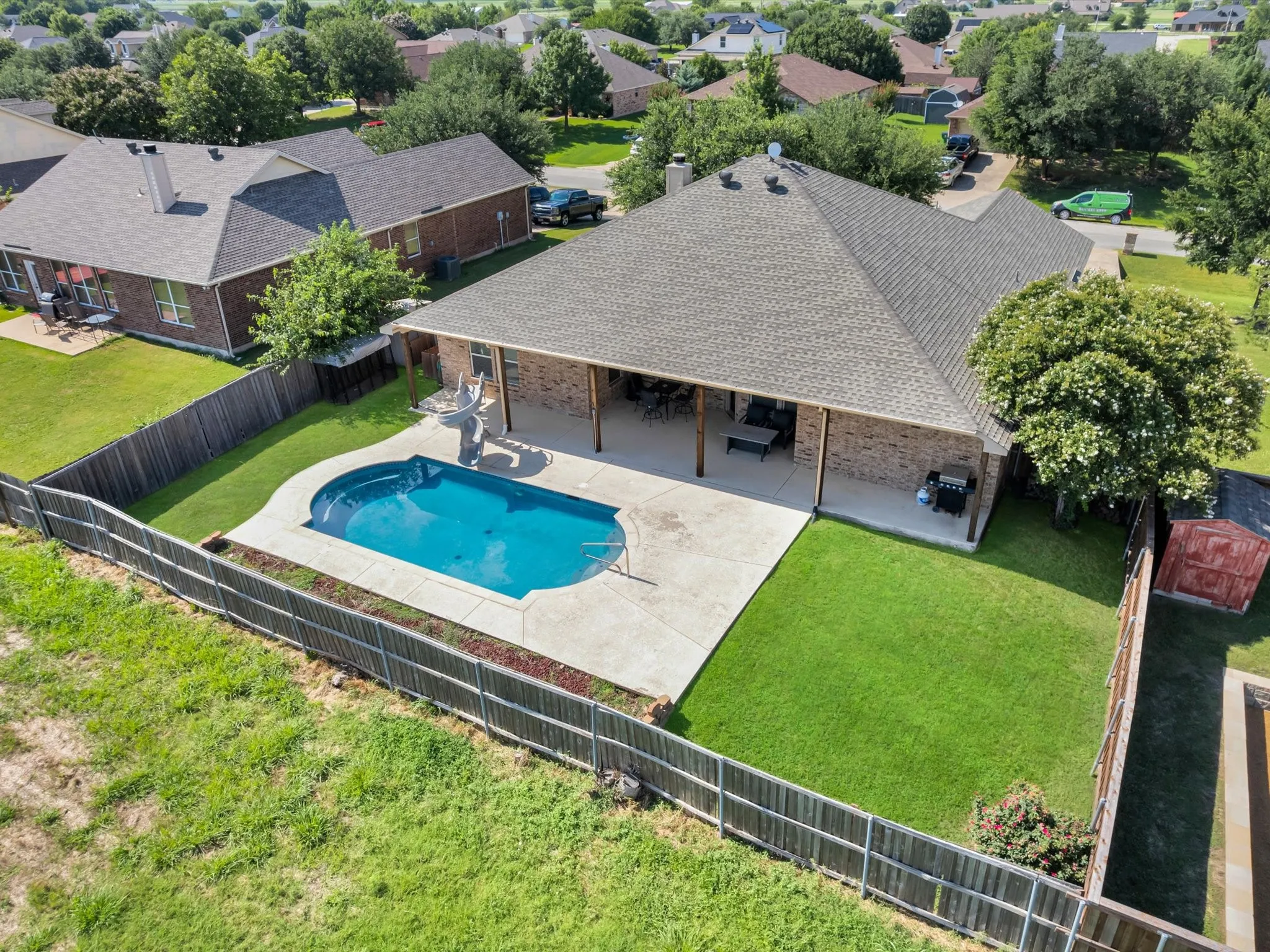 Brick exterior, covered patio, fenced backyard, inground swimming pool, and manicured lawn