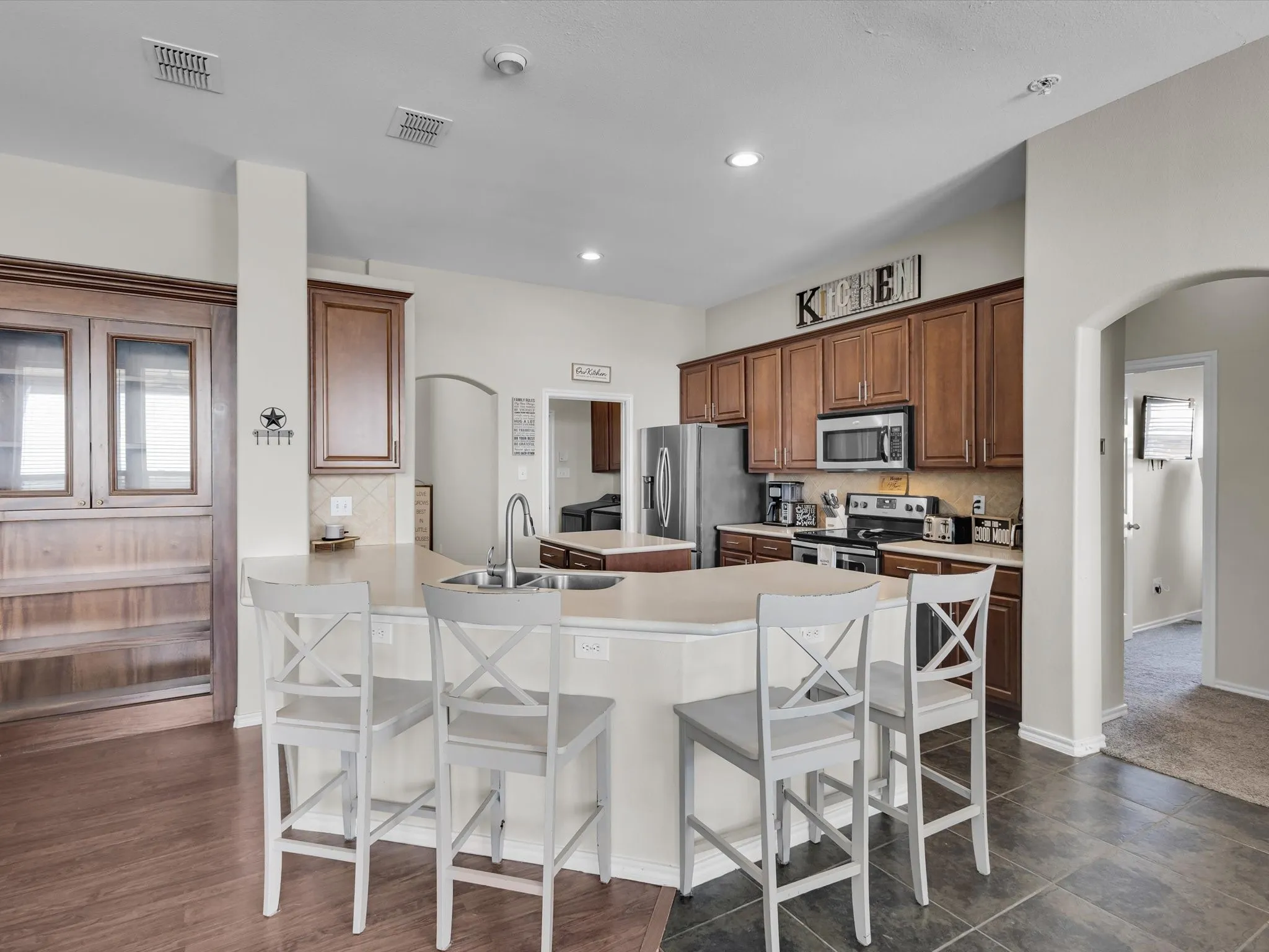 Kitchen featuring a peninsula island, stainless steel appliances, wood cabinetry, and a tile backsplash