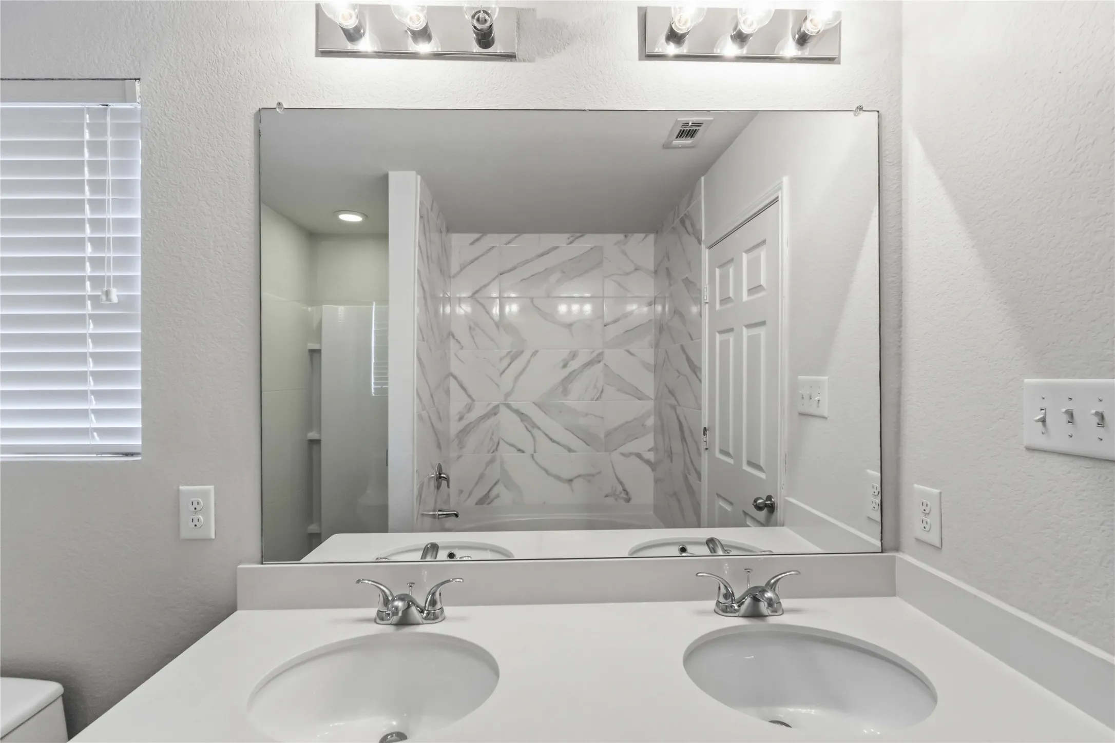Dual vanity with undermount sinks, chrome faucets, and a large frameless mirror