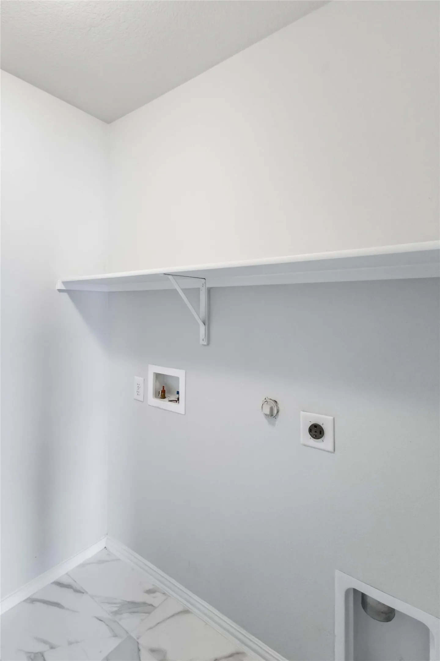Utility room featuring a built-in shelf, appliance hookups, and large format tile flooring