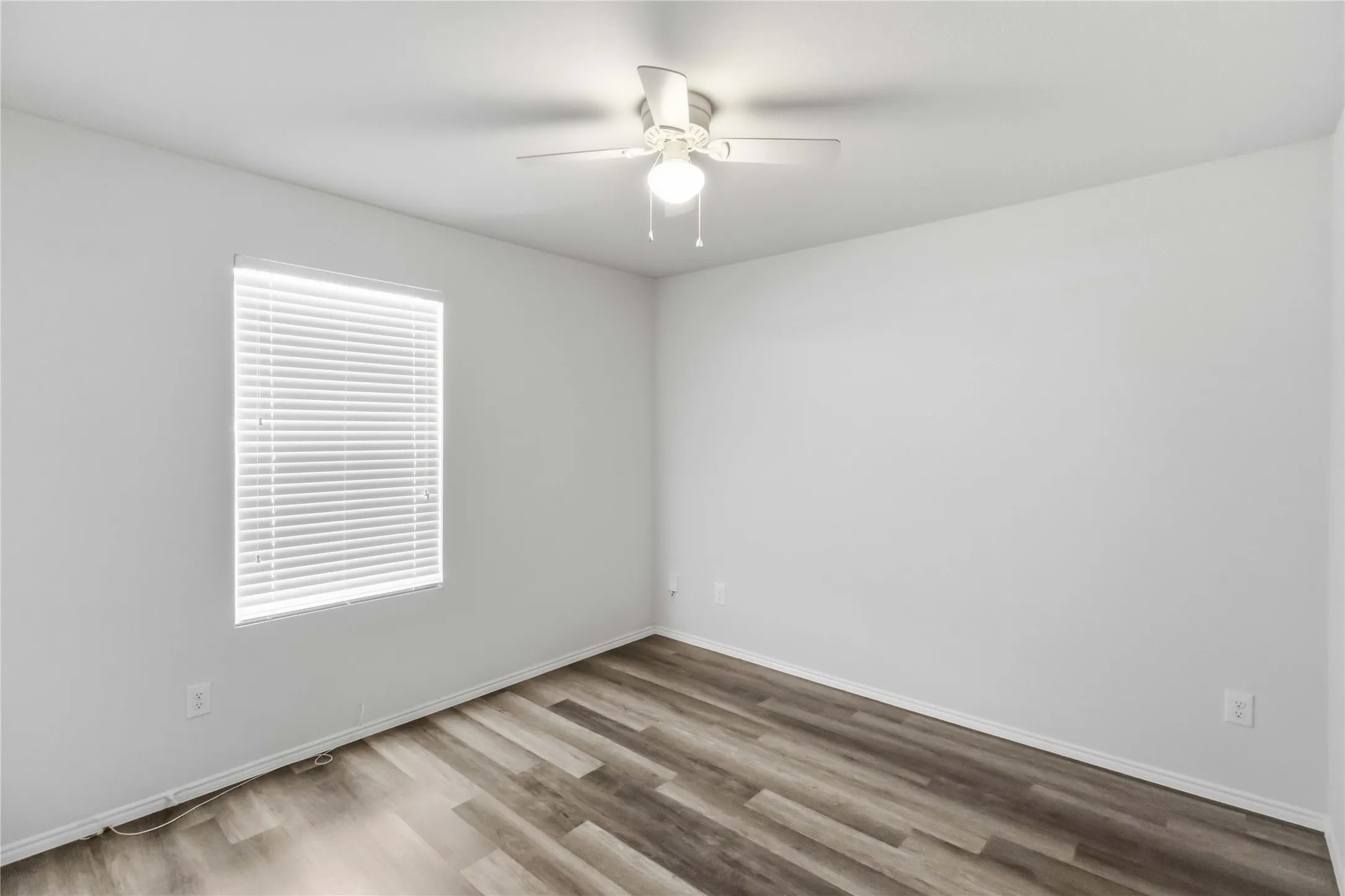Wood-finish flooring with neutral wall tones and a ceiling fan with integrated lighting