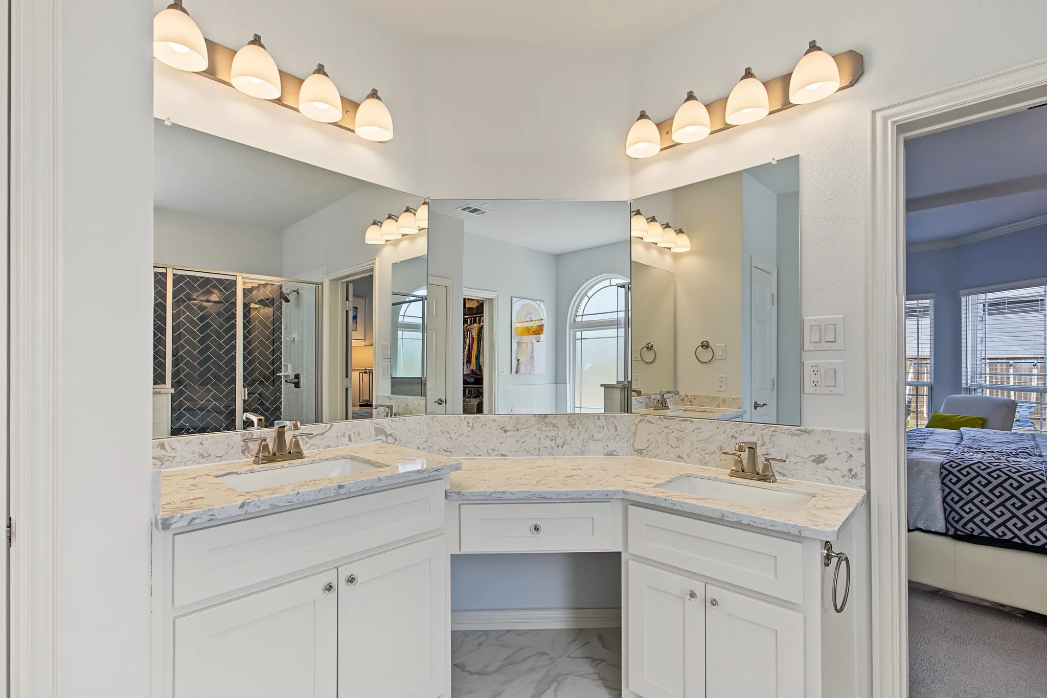 Dual vanity with integrated sinks, white cabinetry, vanity lighting, and a makeup counter