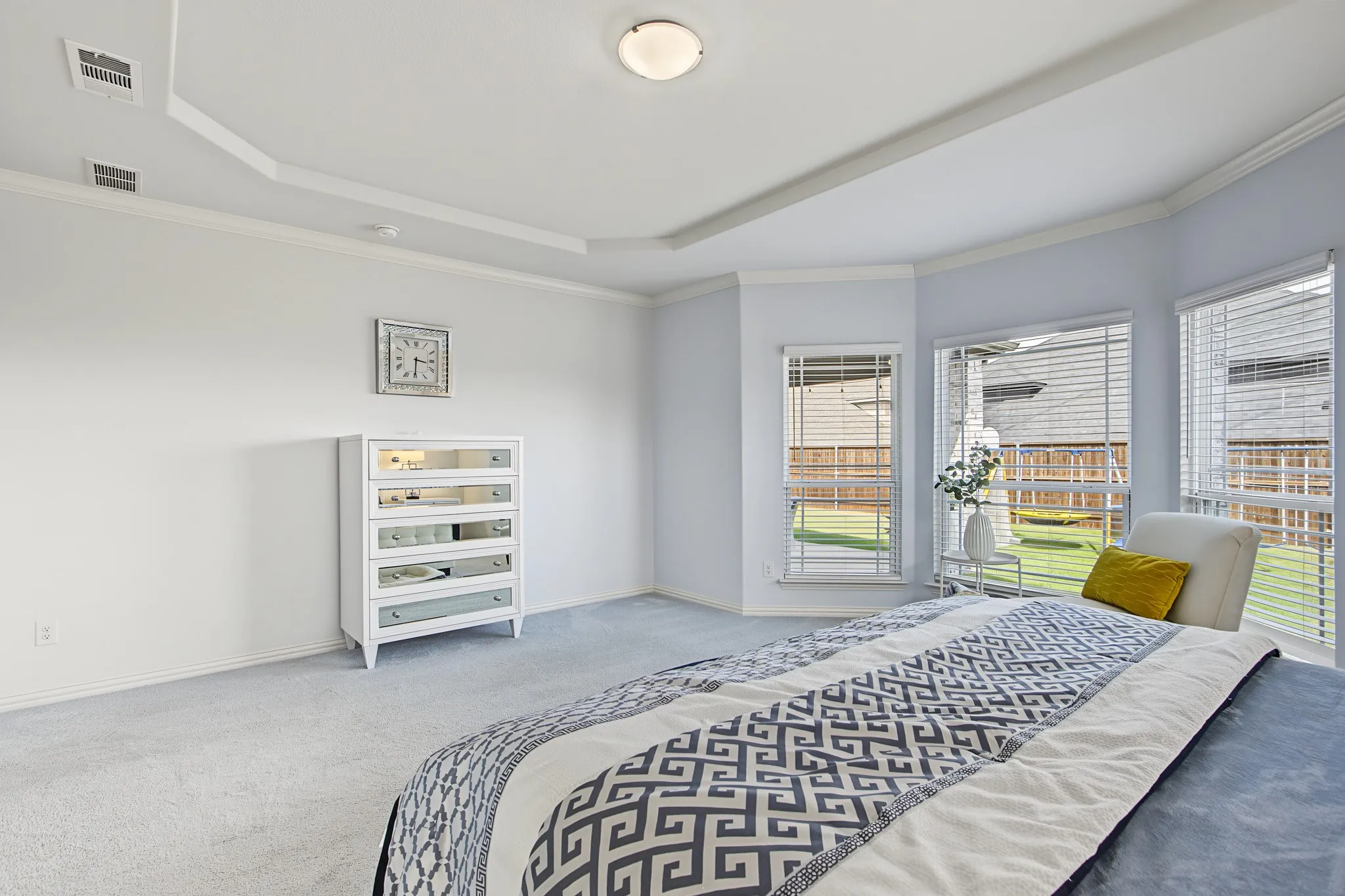 Tray ceiling with crown molding, light-toned carpeting, bay window configuration, multiple windows with blinds, and recessed lighting