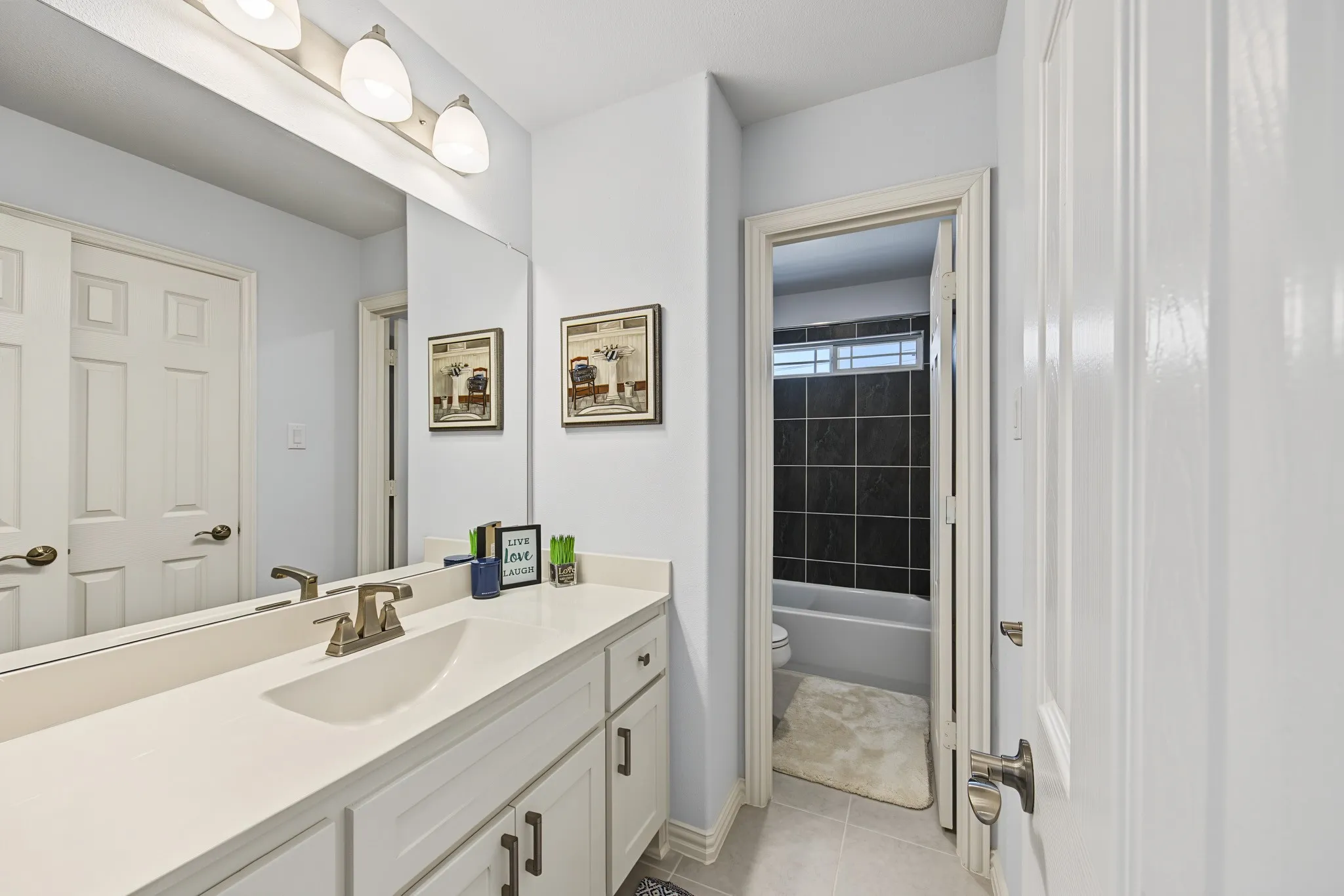Bathroom featuring a single vanity with an integrated sink, brushed nickel faucet, light countertop, and white cabinetry