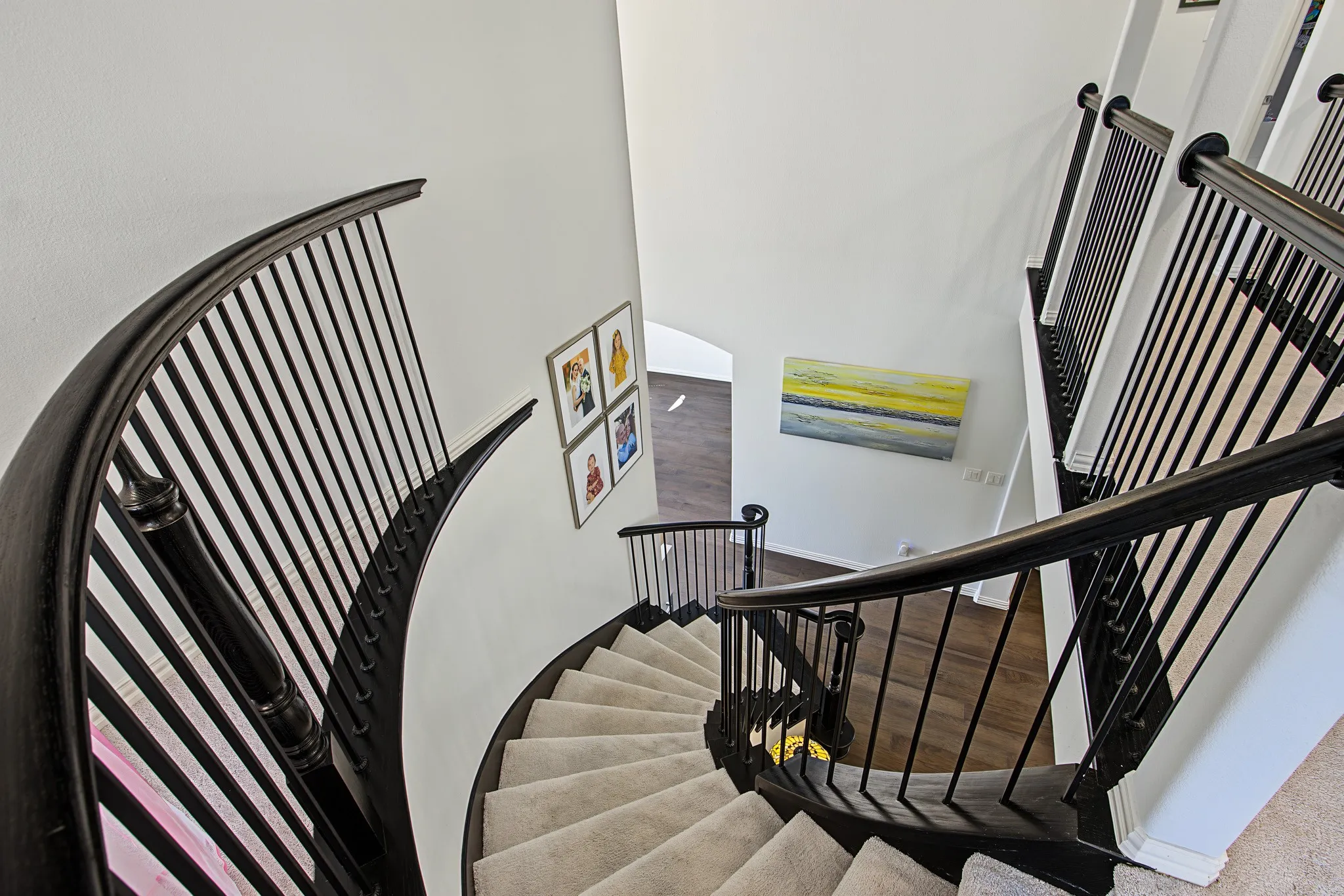 Curved staircase with dark wood-finish handrails and black iron balusters