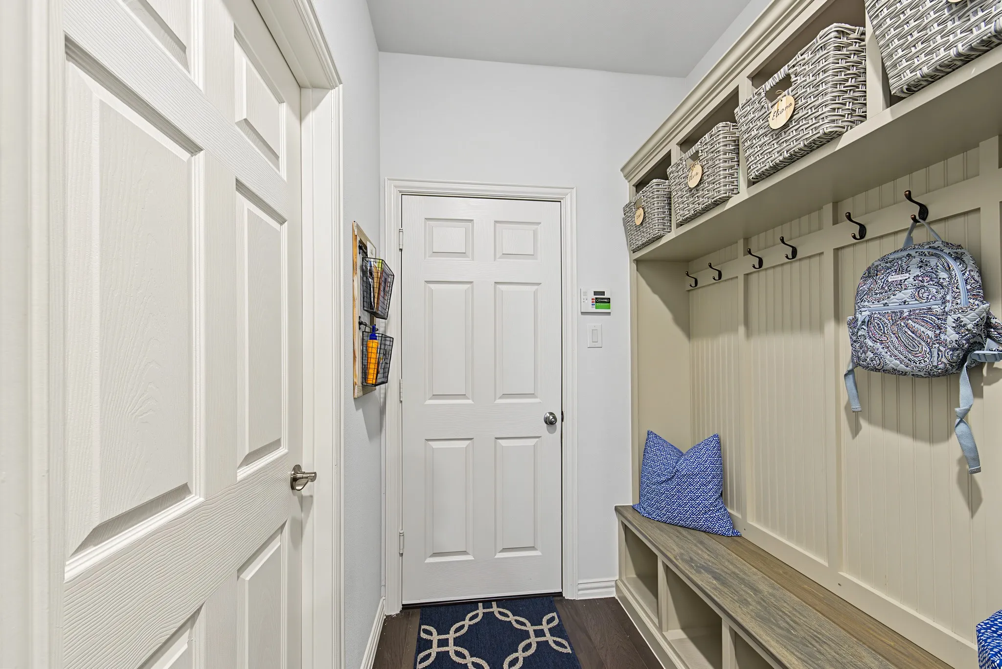 Built-in mudroom bench with storage cubbies, upper shelving, and coat hooks