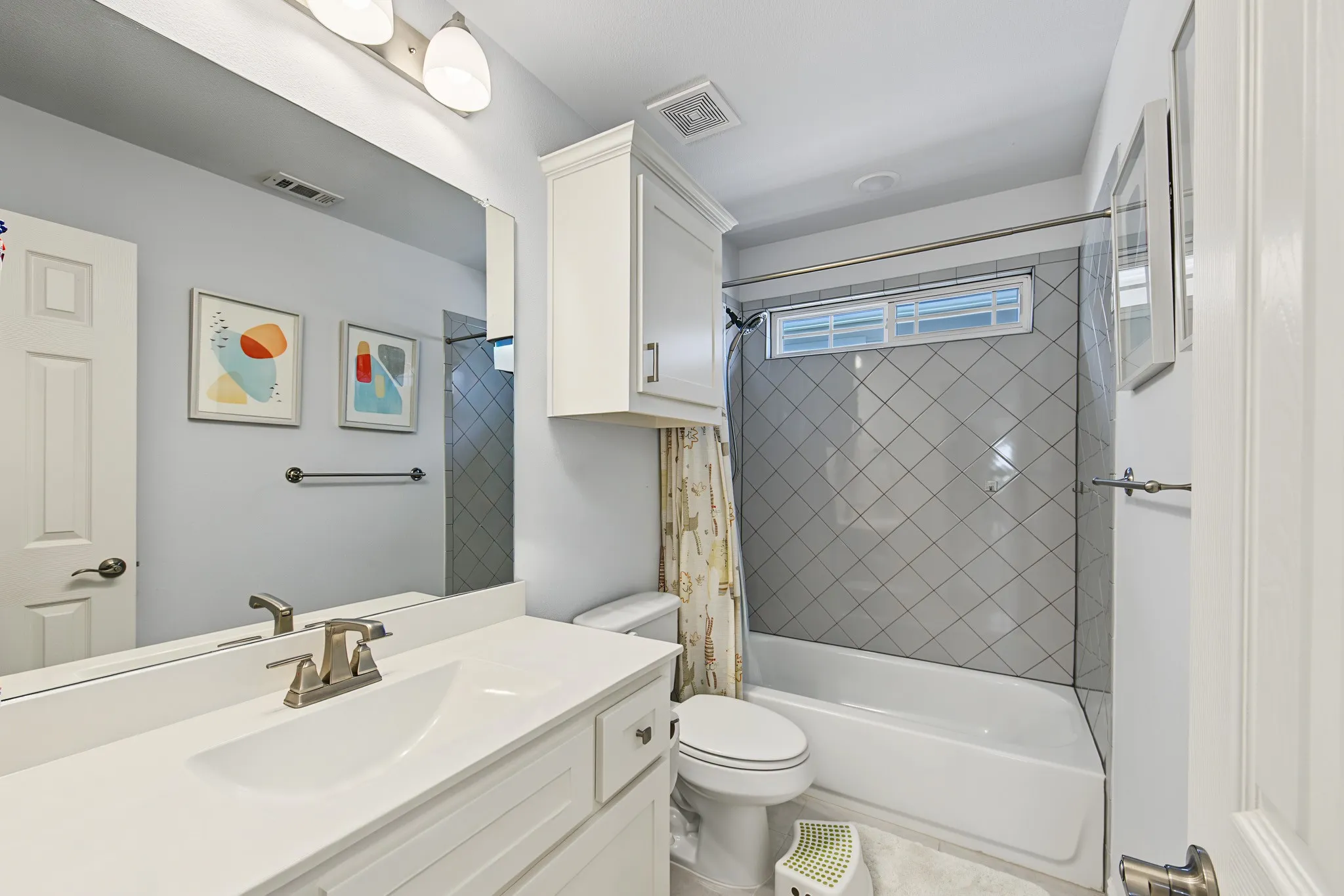 White vanity cabinet with a single basin sink, brushed nickel faucet, and overhead light bar