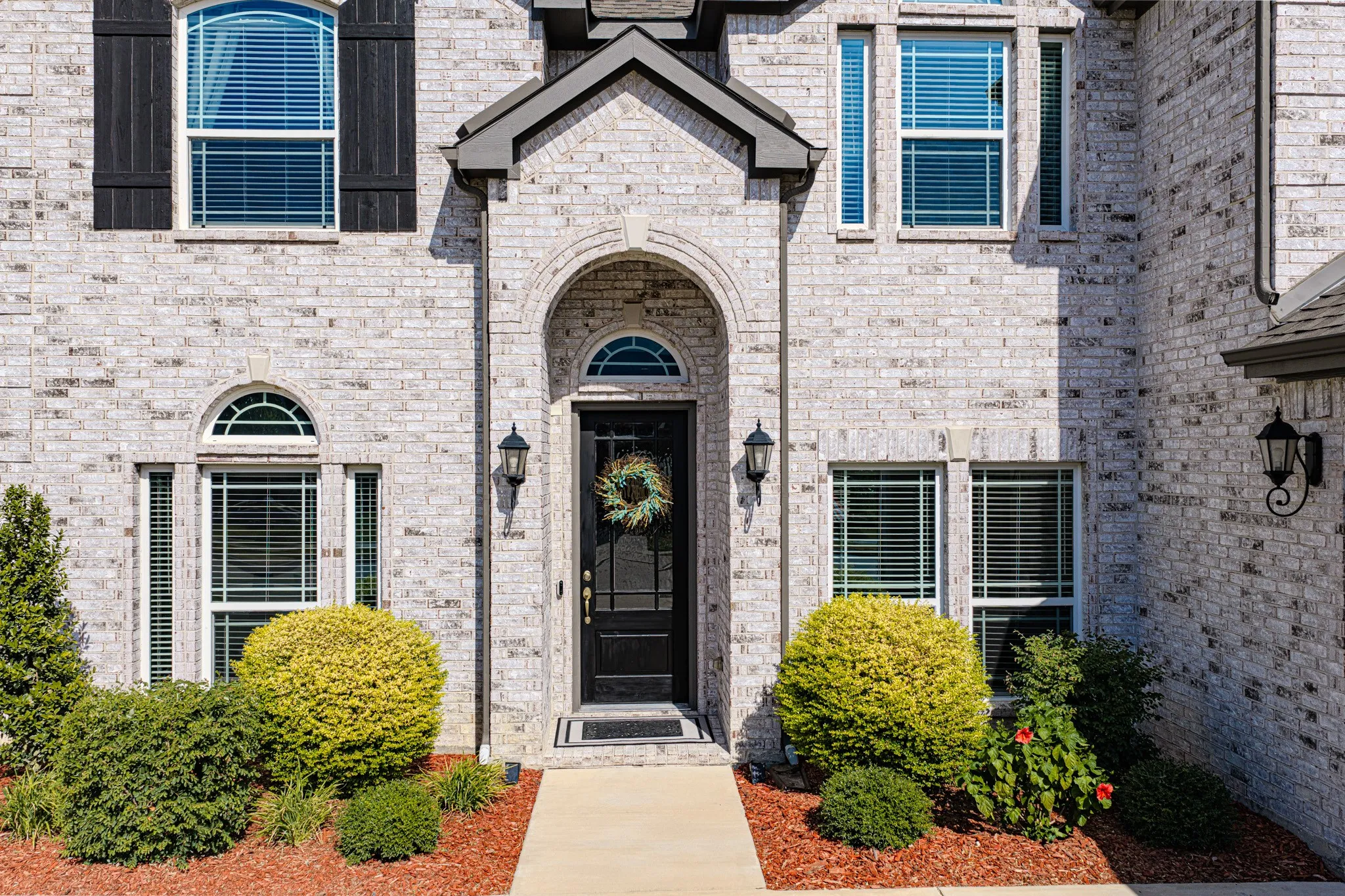 Brick exterior with an arched entryway and dark shutters