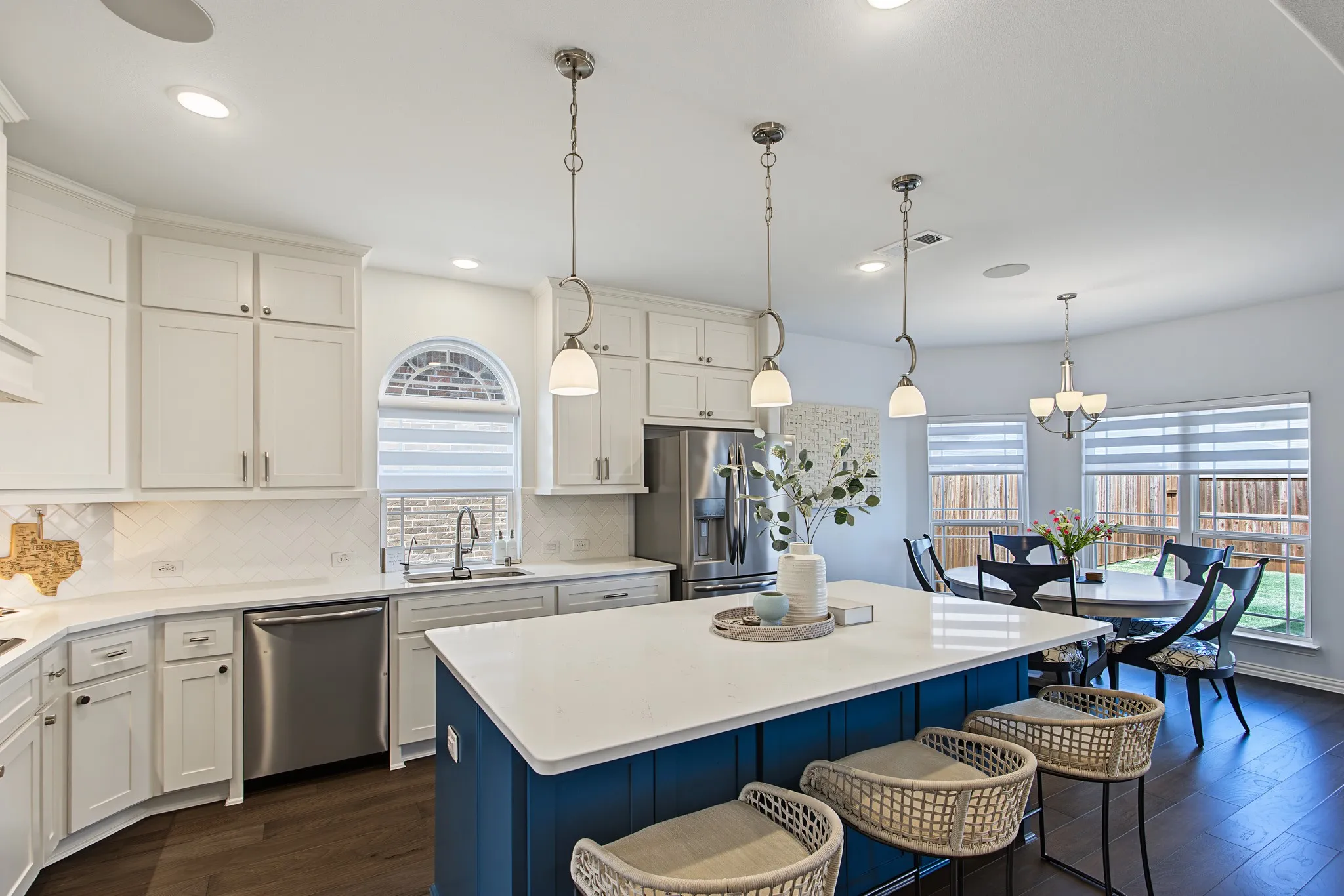 Spacious kitchen with white cabinetry, stainless steel appliances, a center island with seating, and dark wood-finish flooring