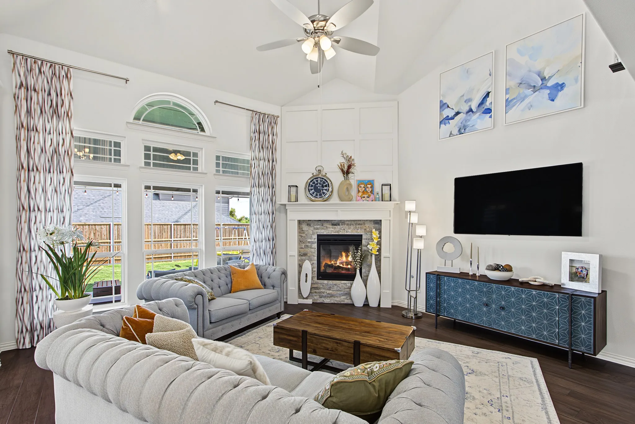 Living area with vaulted ceiling, corner stone fireplace, and wood-finish flooring