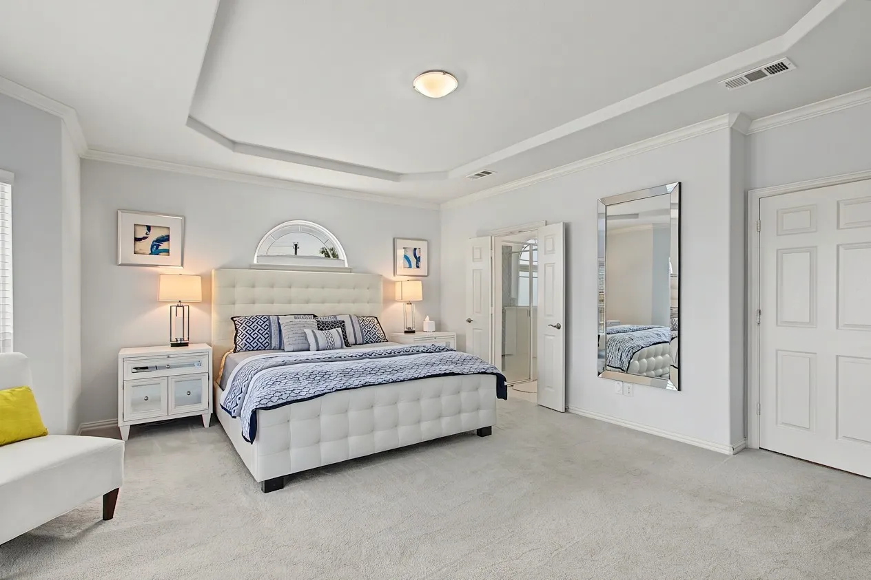 Tray ceiling with crown molding, light-colored carpeting, and a semi-circular wall niche