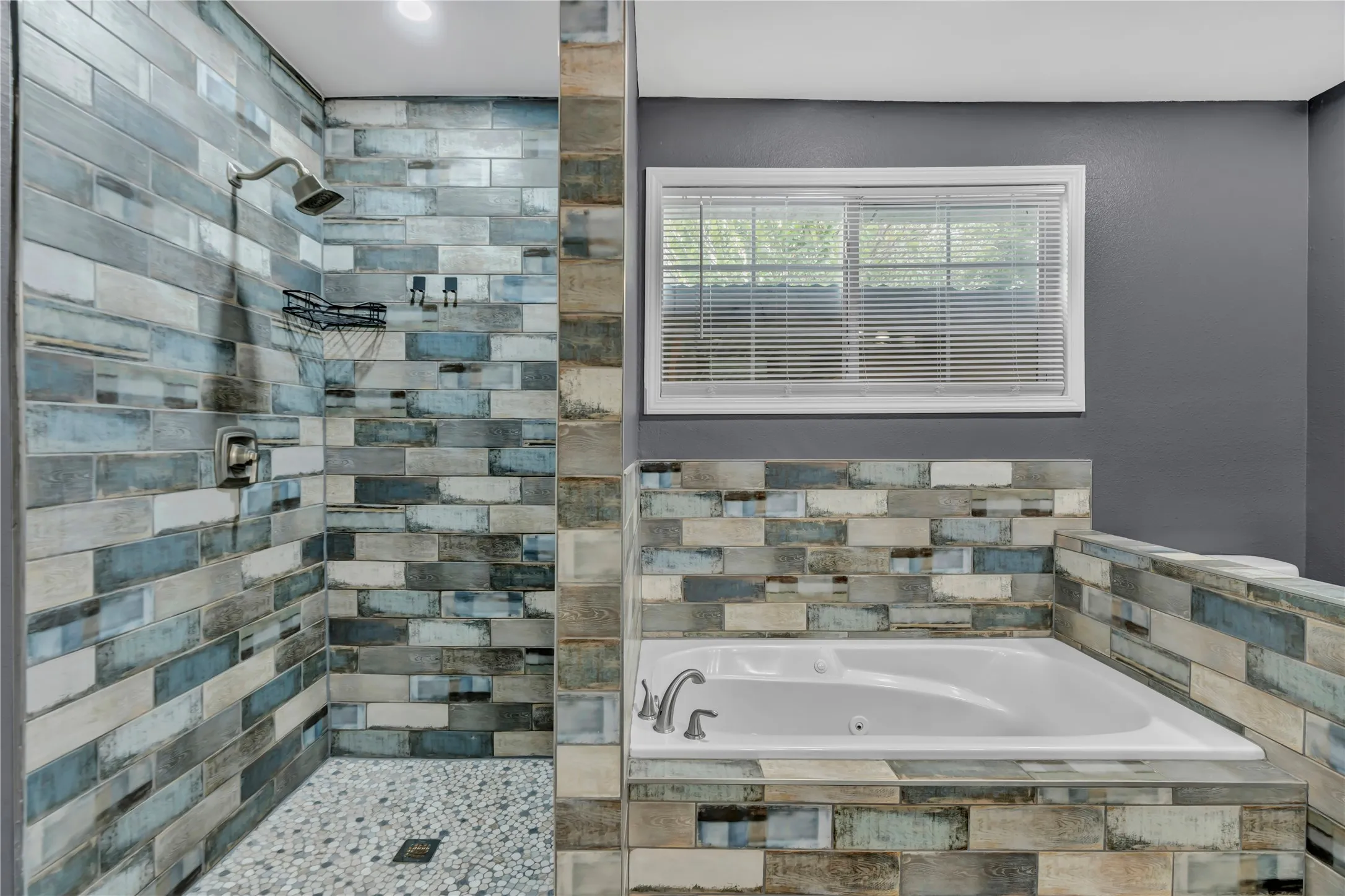 Walk-in shower with pebble tile flooring and a built-in shelf