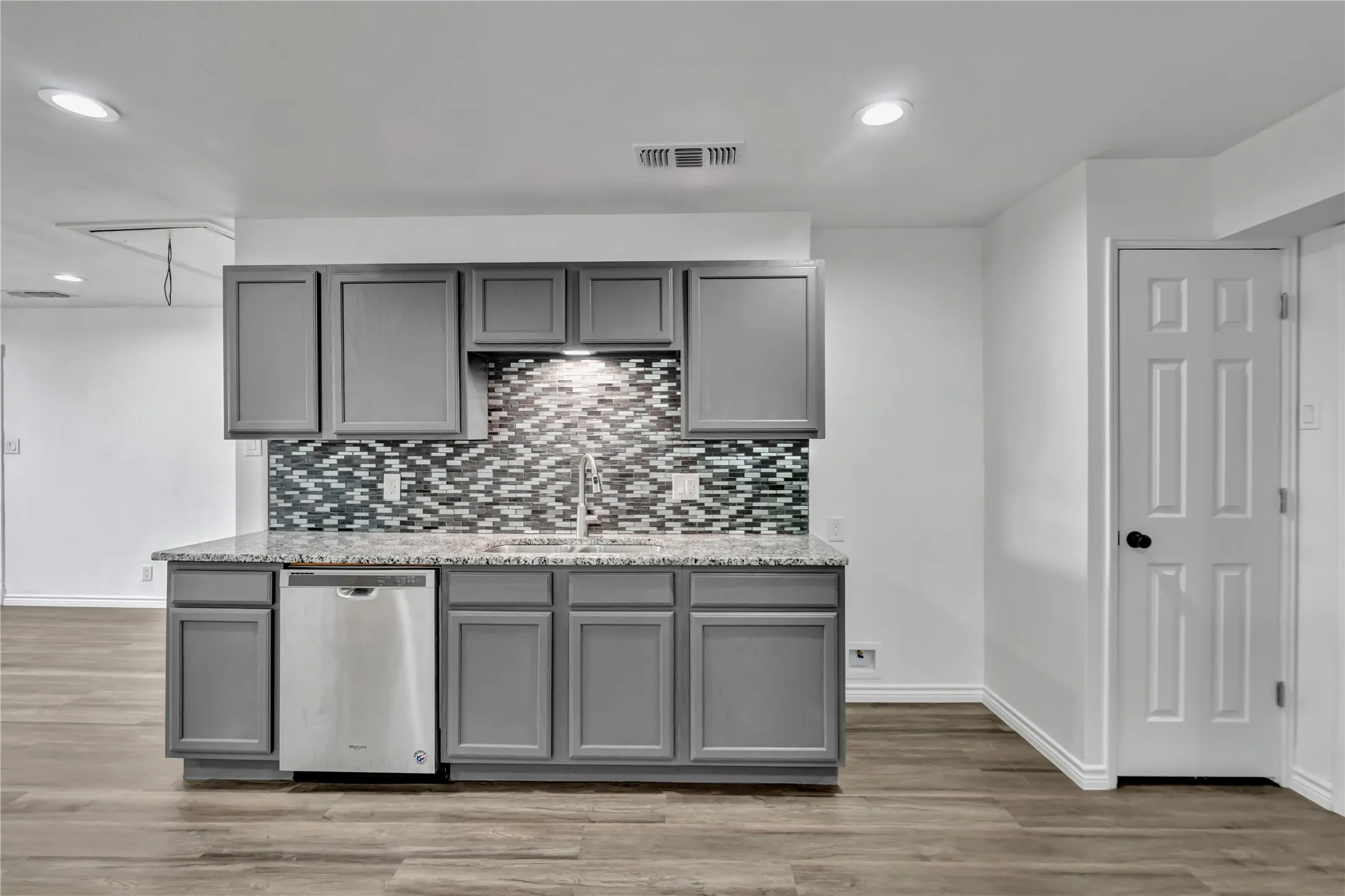 Well-appointed kitchen area featuring gray cabinetry, a mosaic tile backsplash, and a granite-style countertop