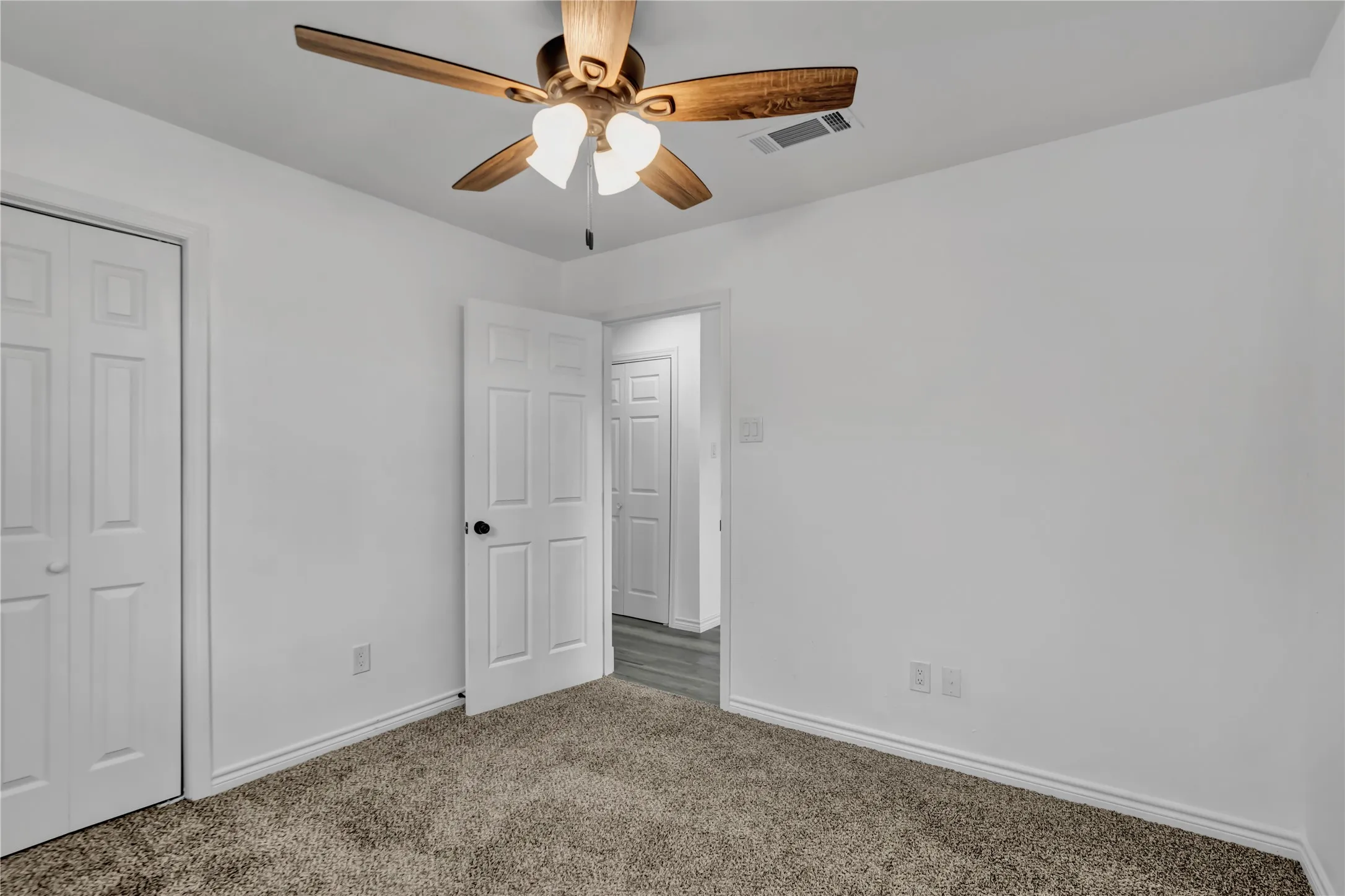 Neutral wall finishes, textured carpeting, and a ceiling fan with integrated lighting