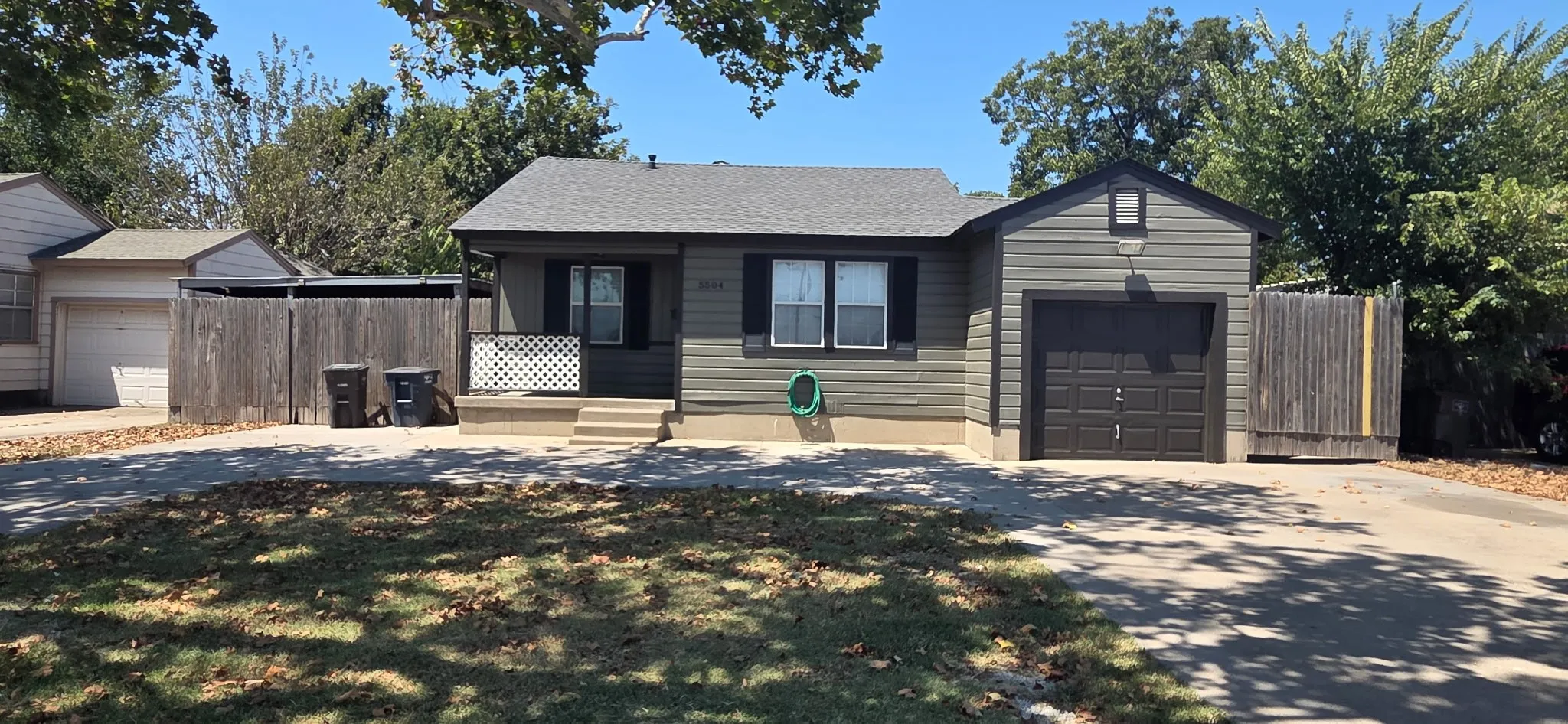 Siding exterior with a covered porch entry, attached garage, and a paved driveway