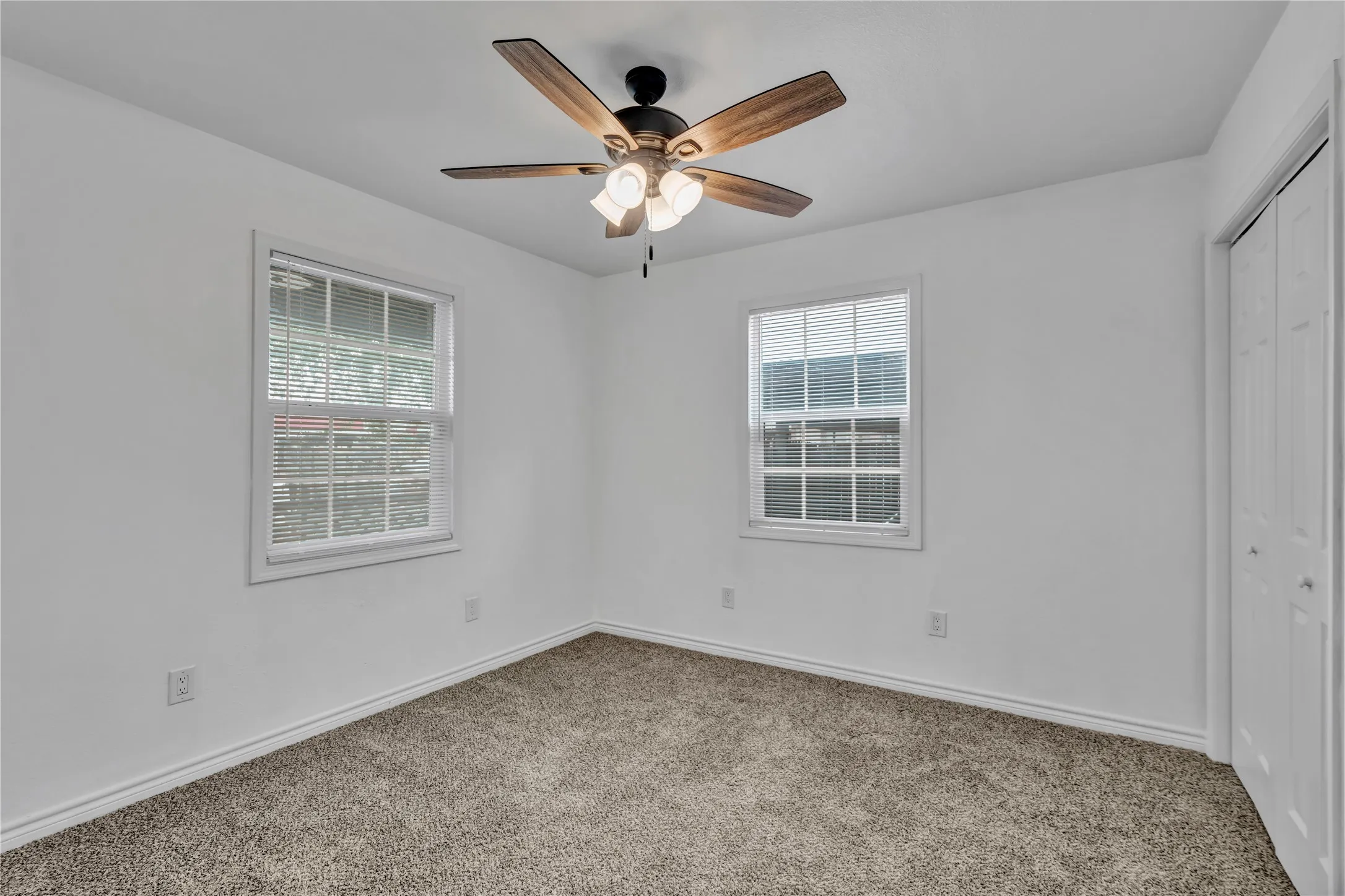 Recessed lighting, ceiling fan with light fixture, two windows with blinds, and neutral carpet