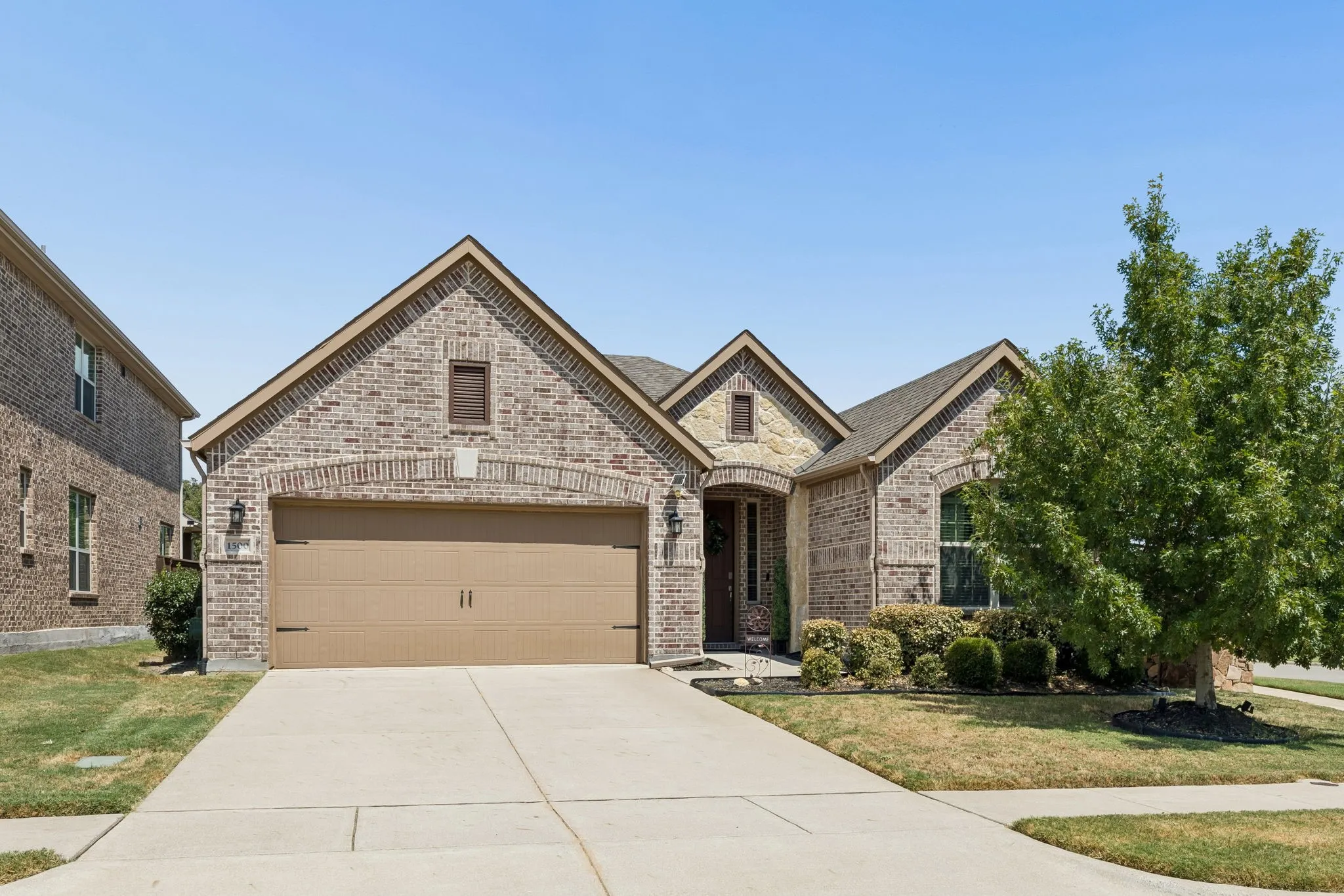Brick exterior with stone accents, an attached two-car garage, and a concrete driveway