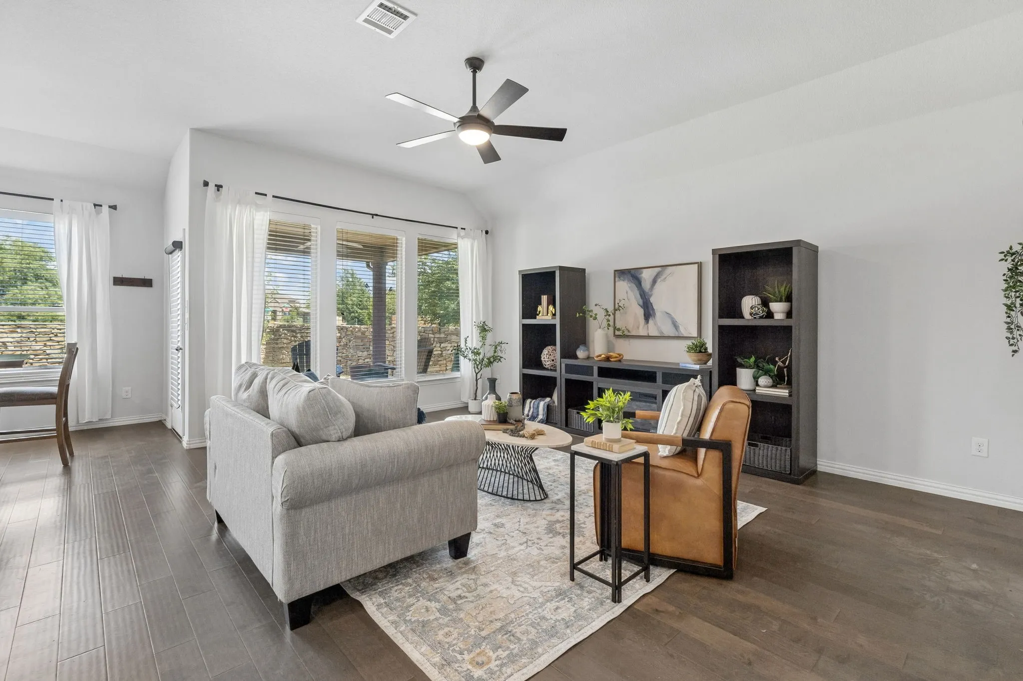 Vaulted ceiling with a ceiling fan, dark wood-finish flooring, and large windows with blinds