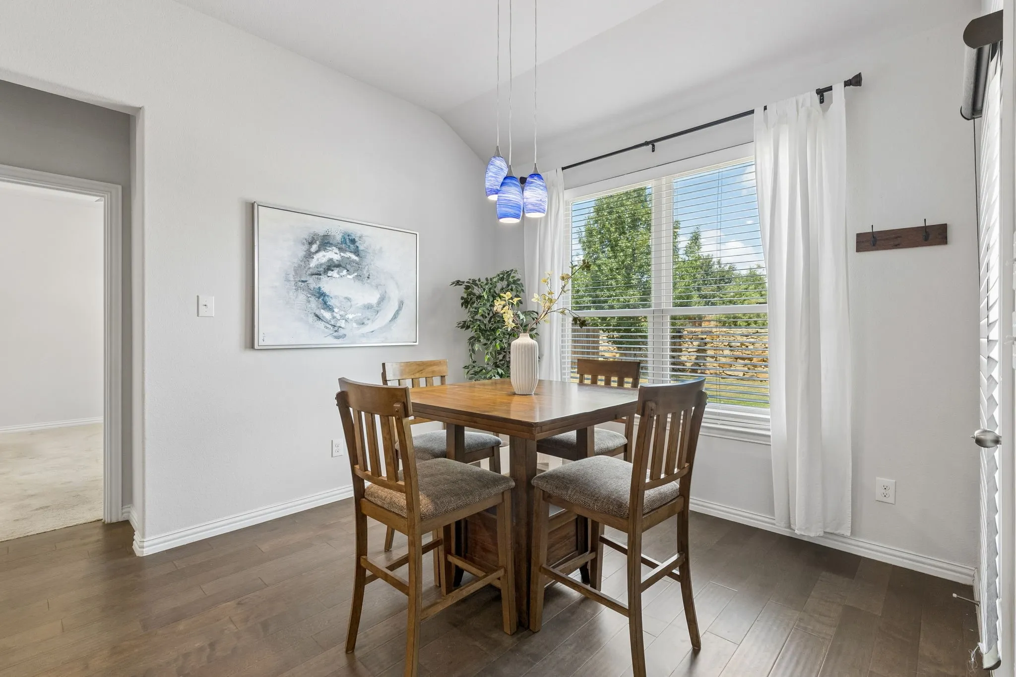 Vaulted ceiling enhancing vertical space, wood-finish flooring, and a large window providing abundant natural light