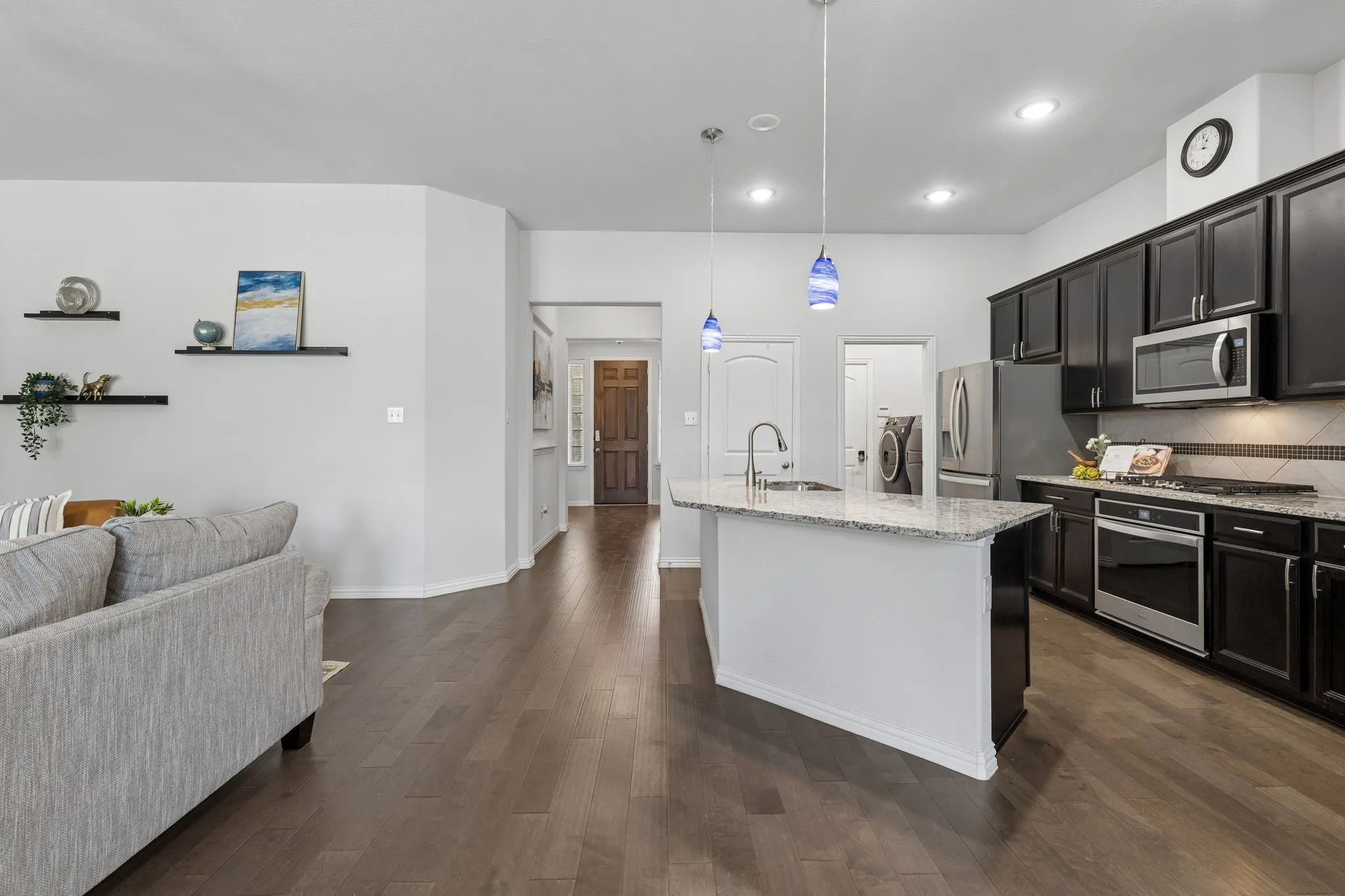 Open-concept kitchen with dark wood-finish cabinetry, stainless steel appliances, and a central island featuring a granite countertop