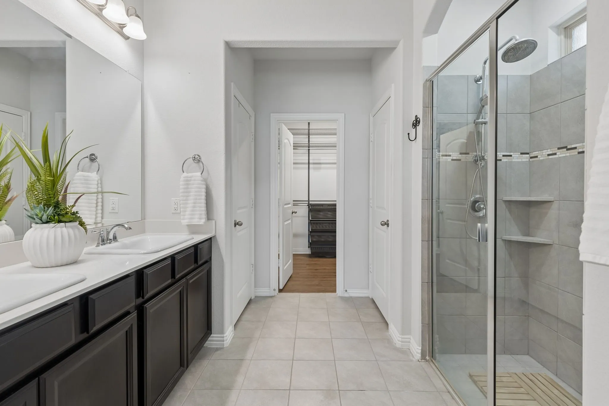 Dual vanity with white countertops, chrome fixtures, and dark wood-finish cabinetry