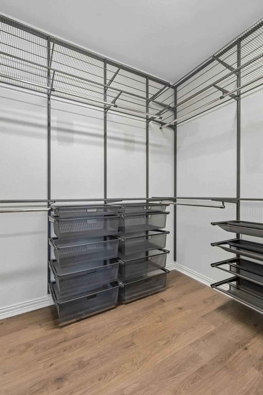 Built-in wire shelving system with multiple hanging rods, integrated drawer storage, and slatted shoe racks