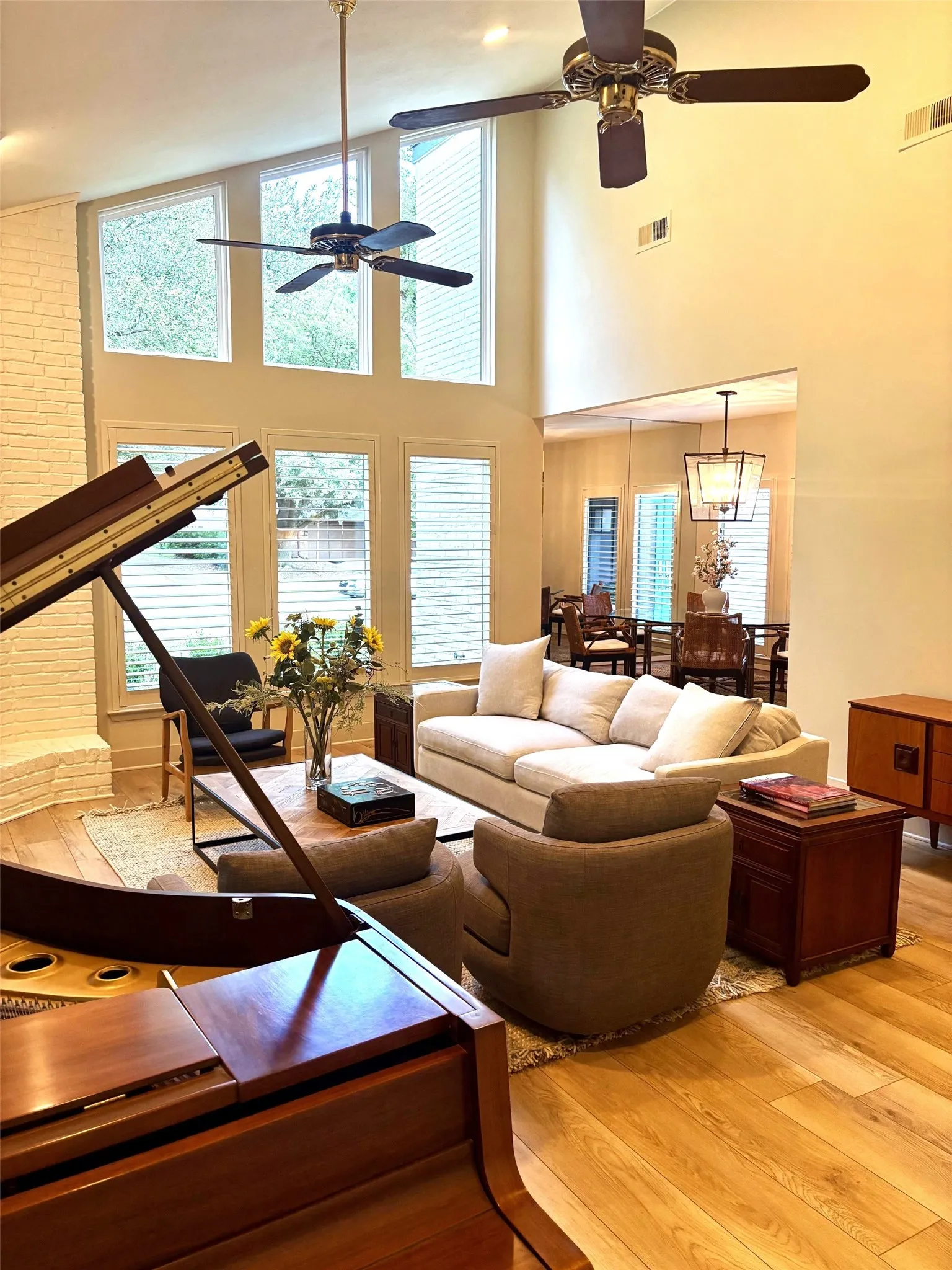 Living area with floor to ceiling windows, baby grand piano and comfortable seating.