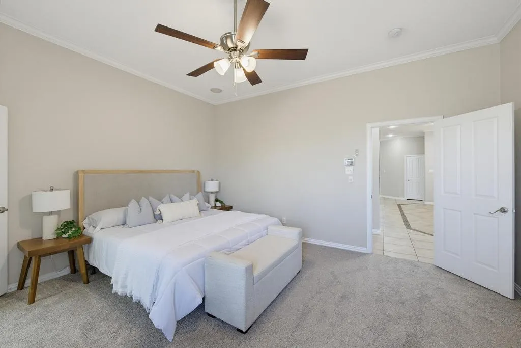 Vaulted ceiling with crown molding and ceiling fan, neutral wall paint, and gray carpeted flooring