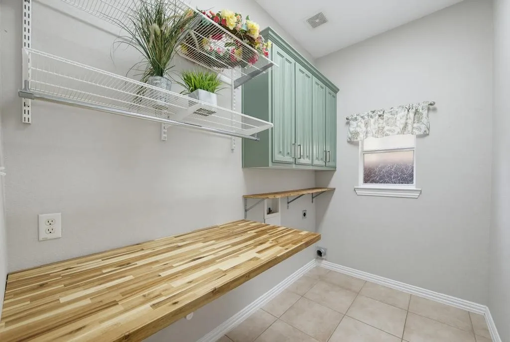 Butcher block countertop with open shelving, closed cabinetry, and tiled flooring