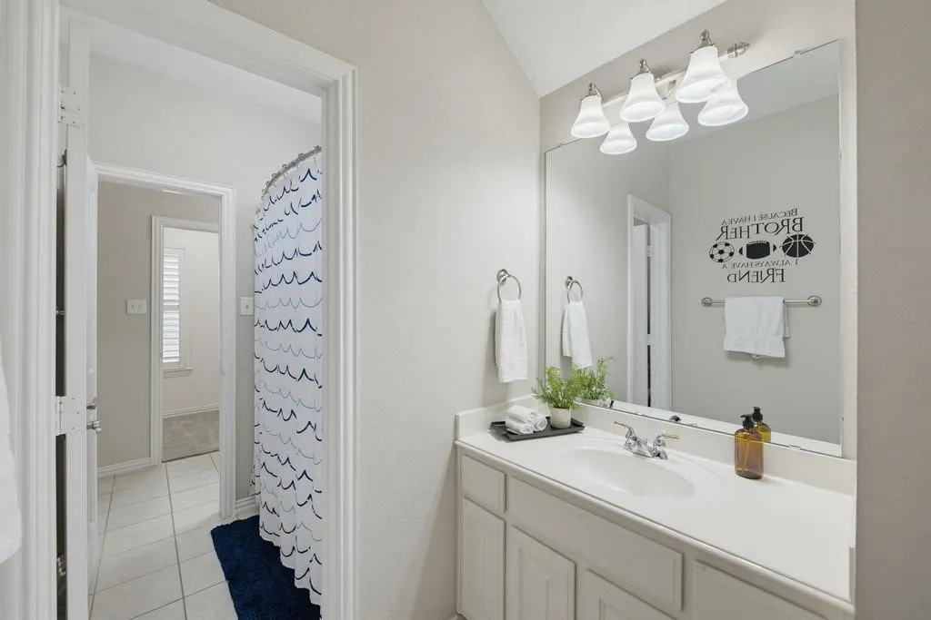 Bathroom featuring a single vanity with an integrated sink, a large mirror, and overhead lighting