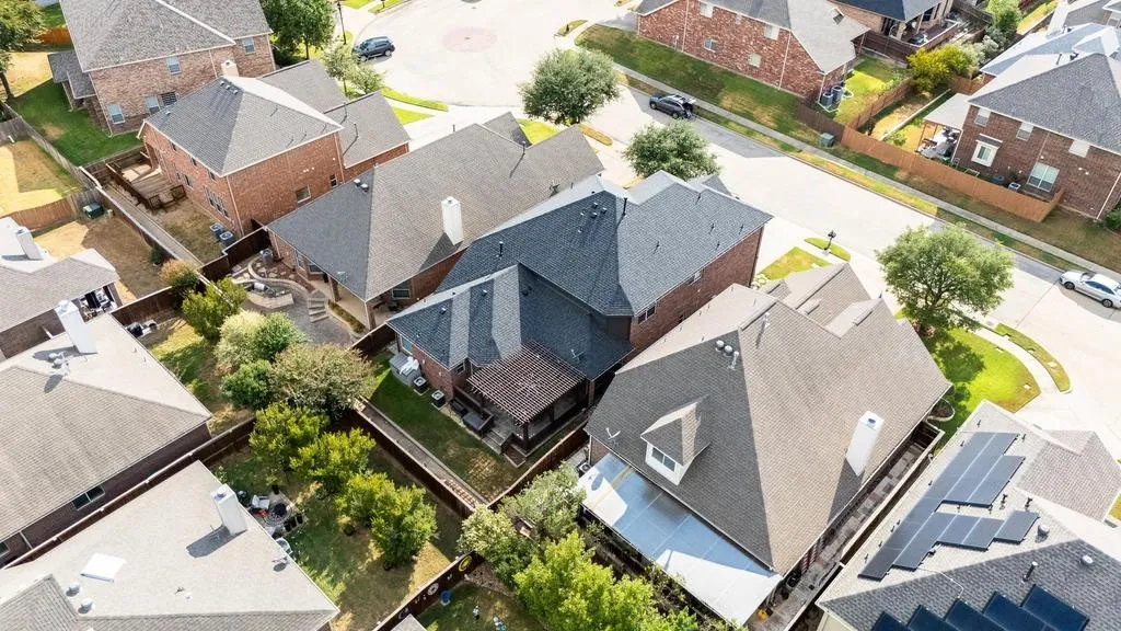 Brick exterior residence featuring a gray shingle roof and a covered patio