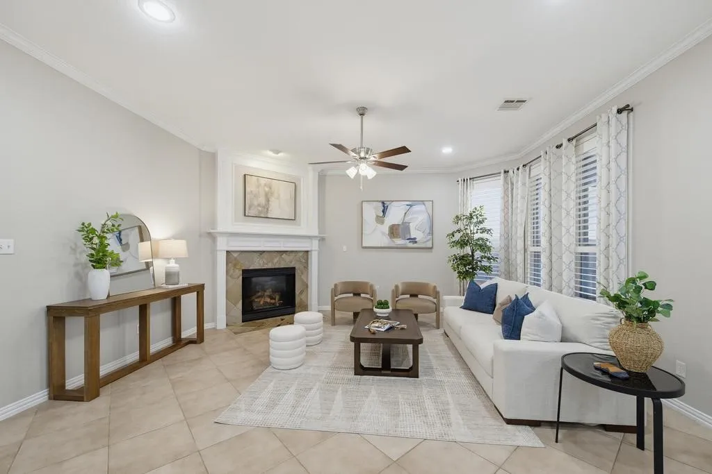 Living area featuring tile flooring, a fireplace with a stone surround, recessed lighting, crown molding, and a ceiling fan