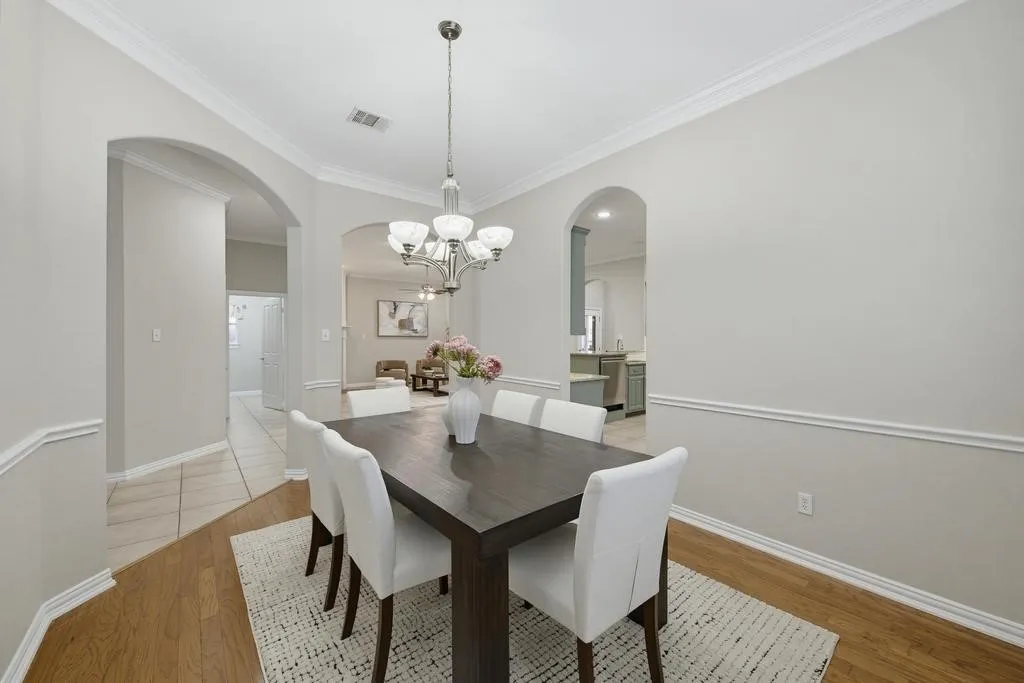 Crown molding, arched doorways, wood-finish flooring, ceramic tile flooring, and a six-light chandelier