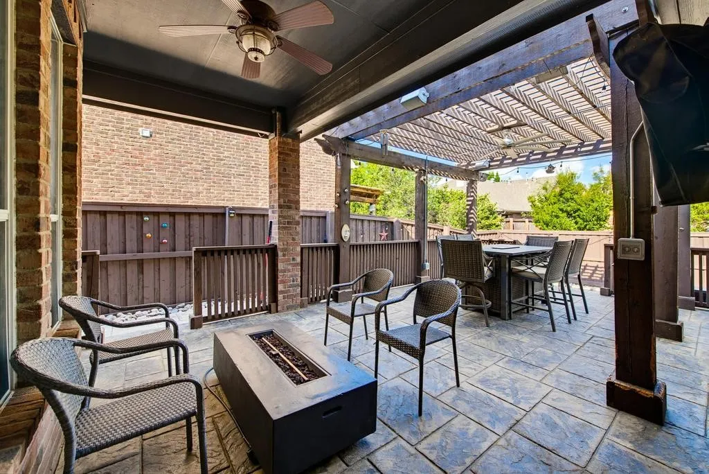 Covered patio featuring a ceiling fan, stamped concrete flooring, and a wood pergola